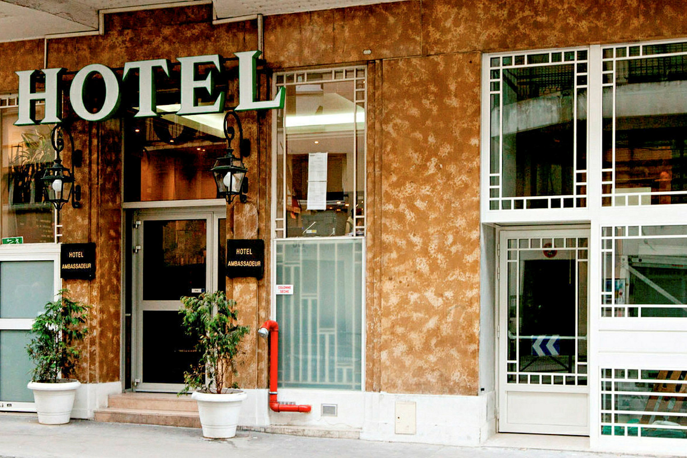 Forsiden av et hotell med et skilt som sier 'Hotel Ambassadeur'. (AI-generert tekst)