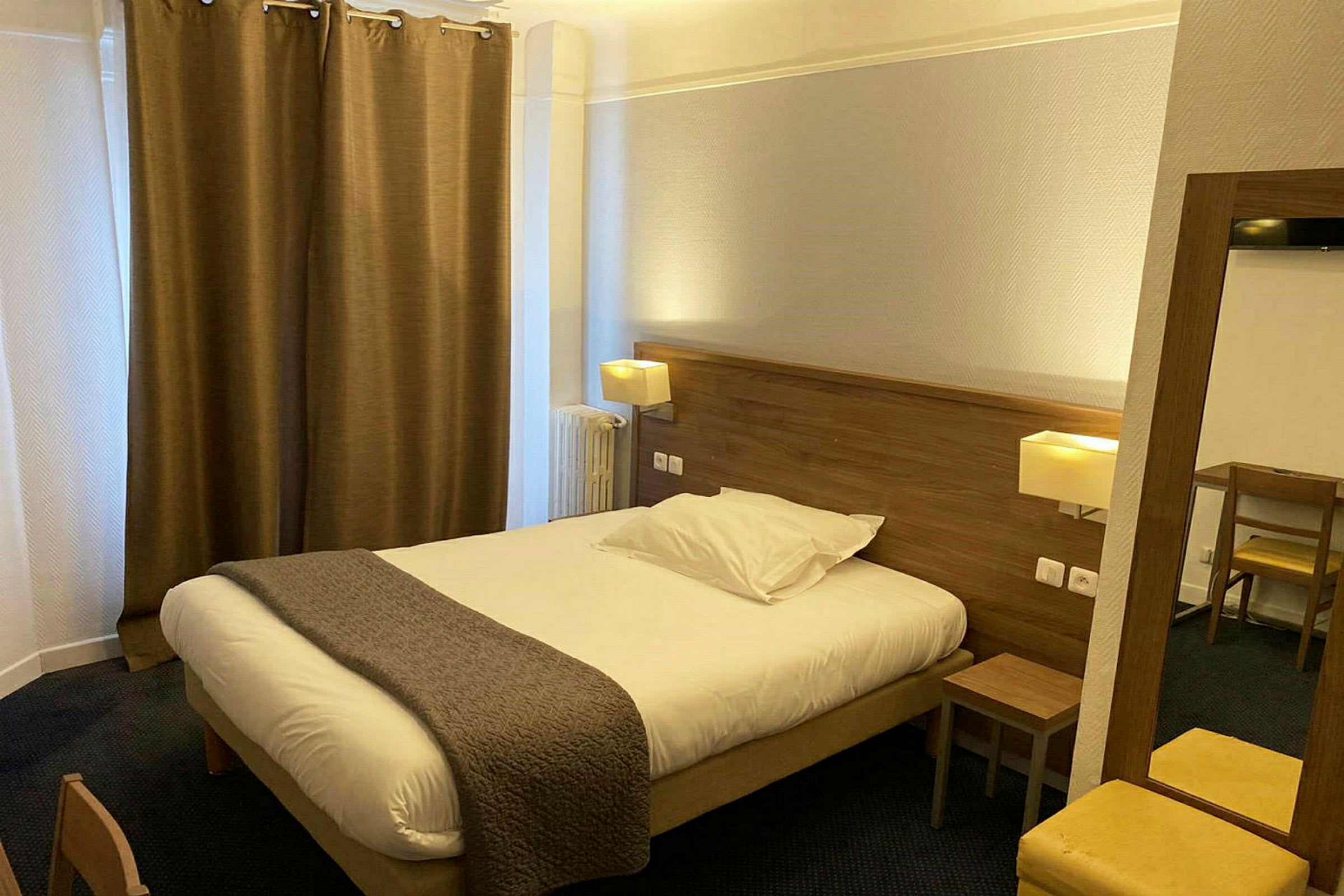 Hotellrom med en dobbeltseng, nattbord og skrivebord. (AI-generert tekst)