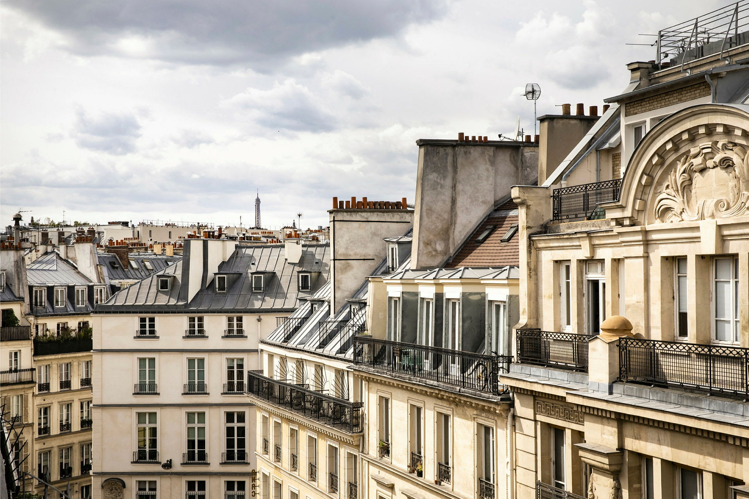 Bilde av parisiske bygninger med typiske tak, med Eiffeltårnet synlig i bakgrunnen. (AI-generert tekst)