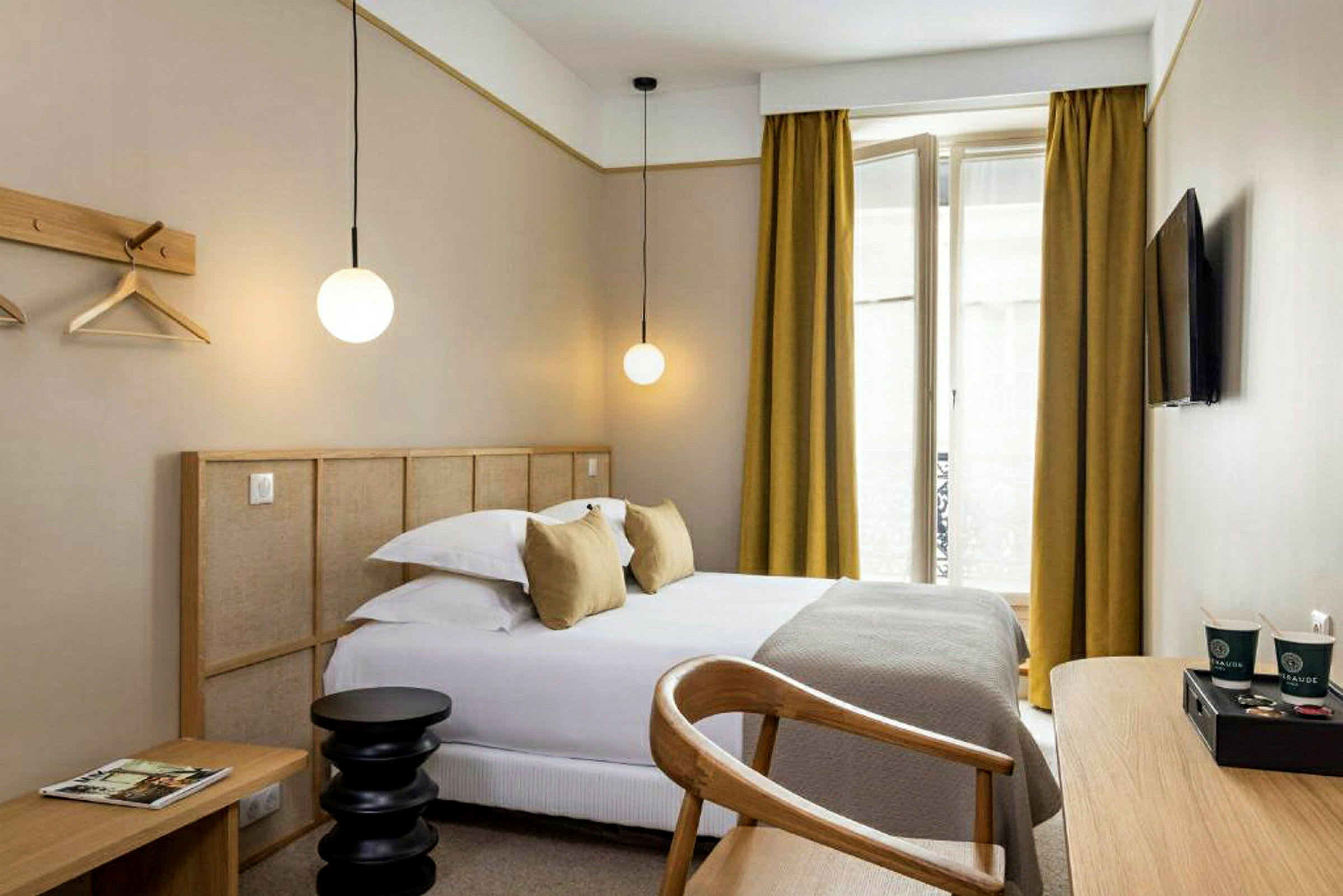 Et moderne hotellrom med en seng, skrivebord og en TV på veggen. (AI-generert tekst)