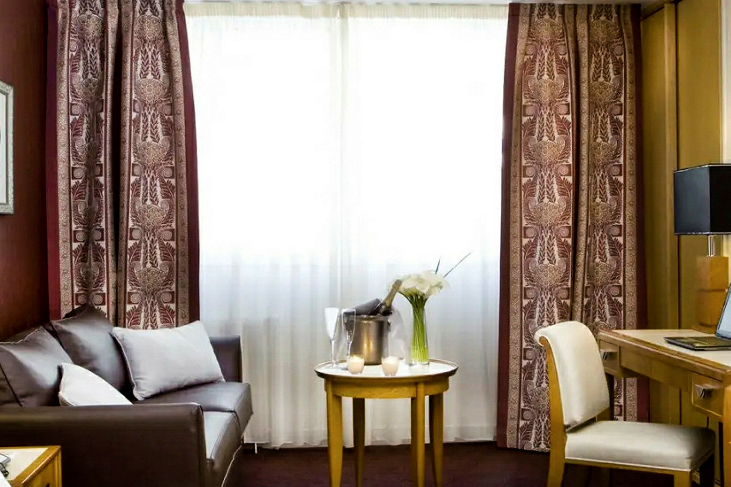 Et hotellrom med en sofa, et bord og en arbeidsstasjon. (AI-generert tekst)