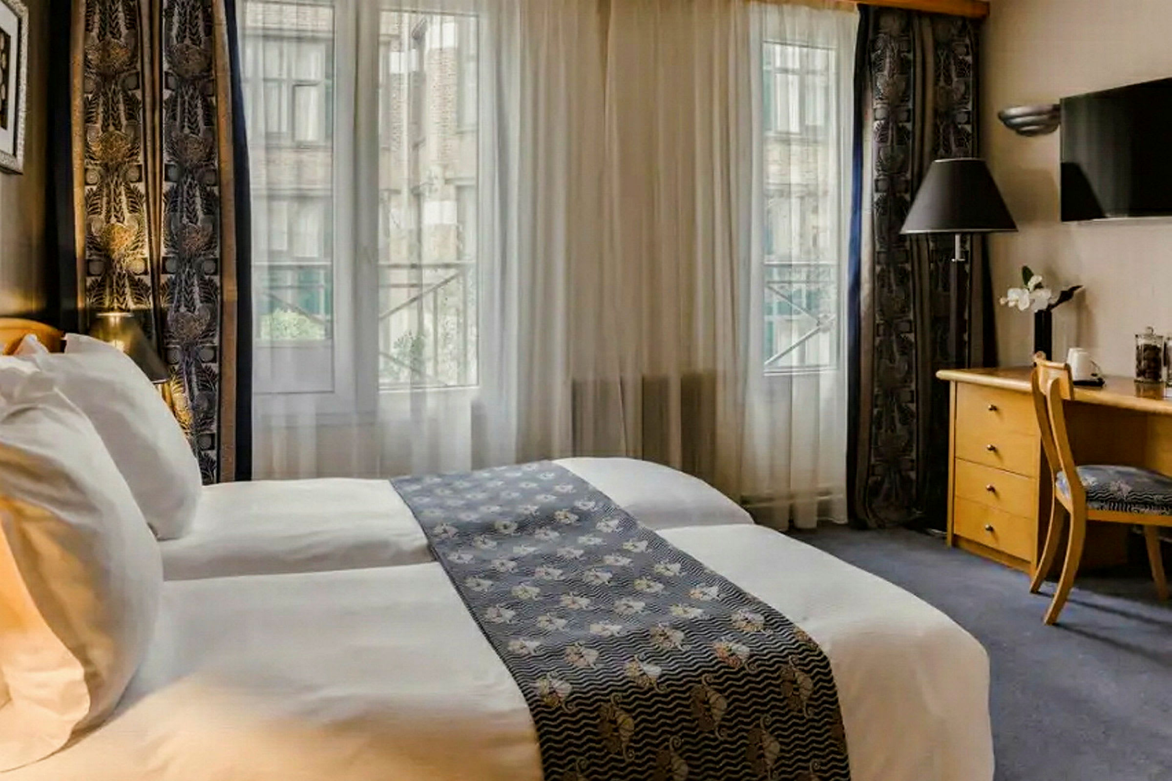 Hotellrom med to senger, skrivebord og vindu med utsikt. (AI-generert tekst)