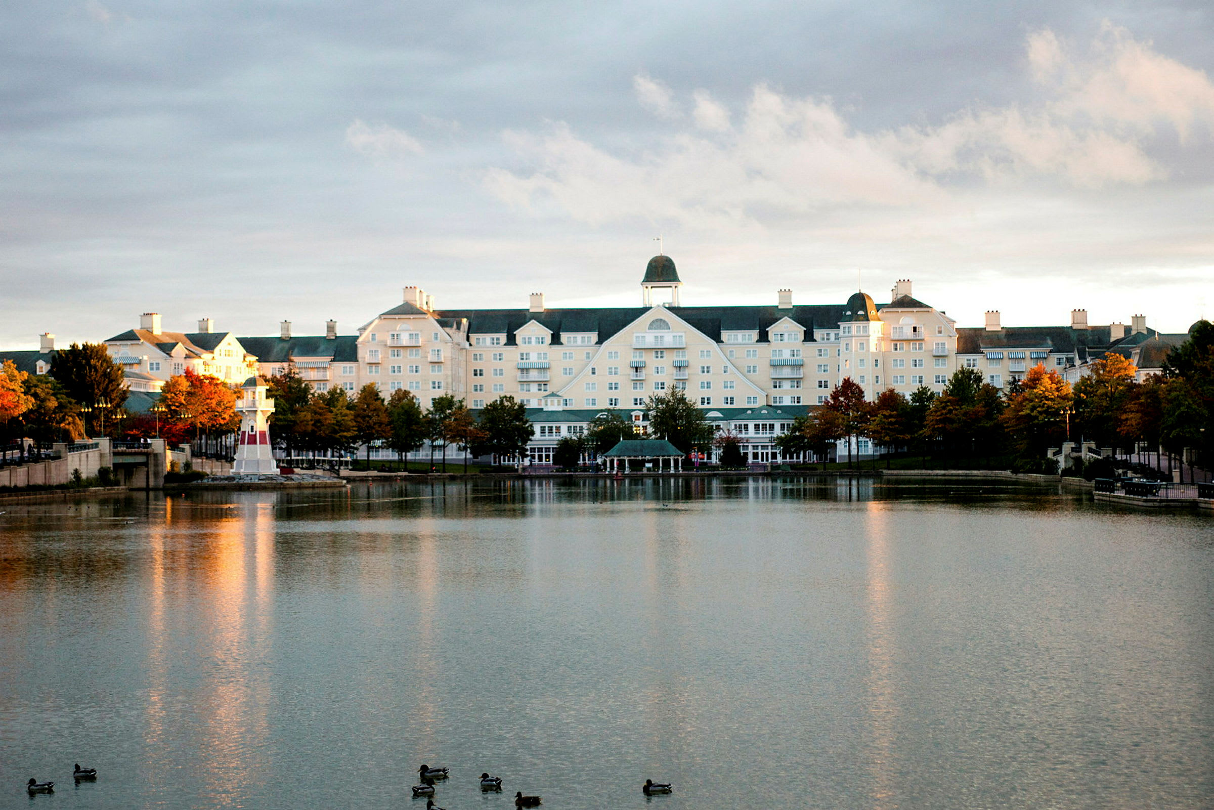 Hotellbygningen ved en innsjø med et lite fyrtårn. (AI-generert tekst)