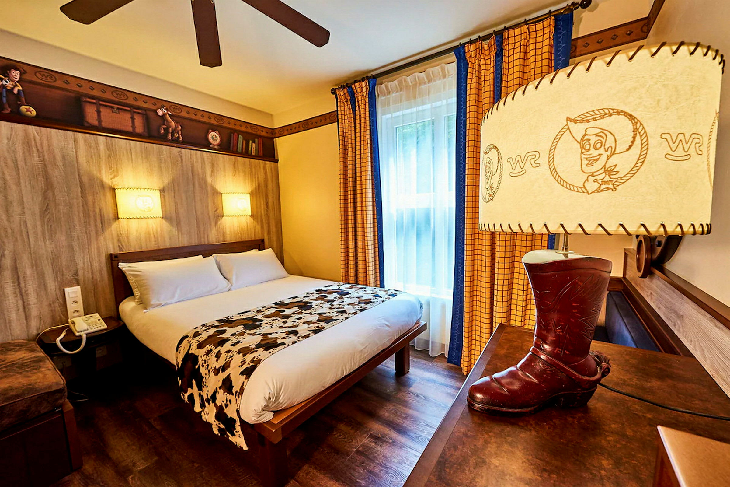 Et tematisert hotellrom med en dobbeltseng, dekorert med leketøysinspirerte detaljer og en lampe formet som en cowboystøvel. (AI-generert tekst)