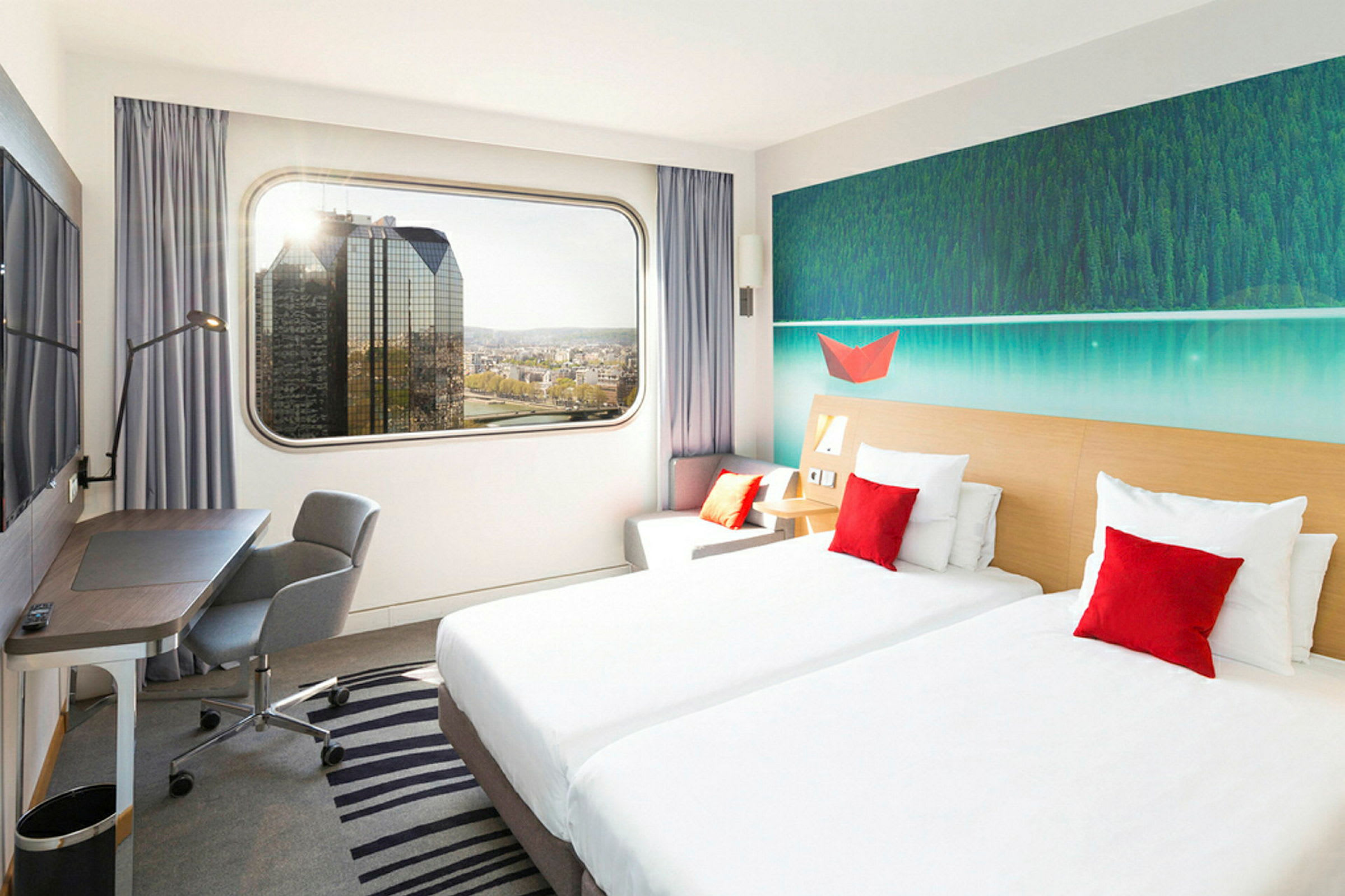 Et hotellrom med to enkeltsenger, en arbeidsplass og en stor vindusutsikt over byens skyline. (AI-generert tekst)