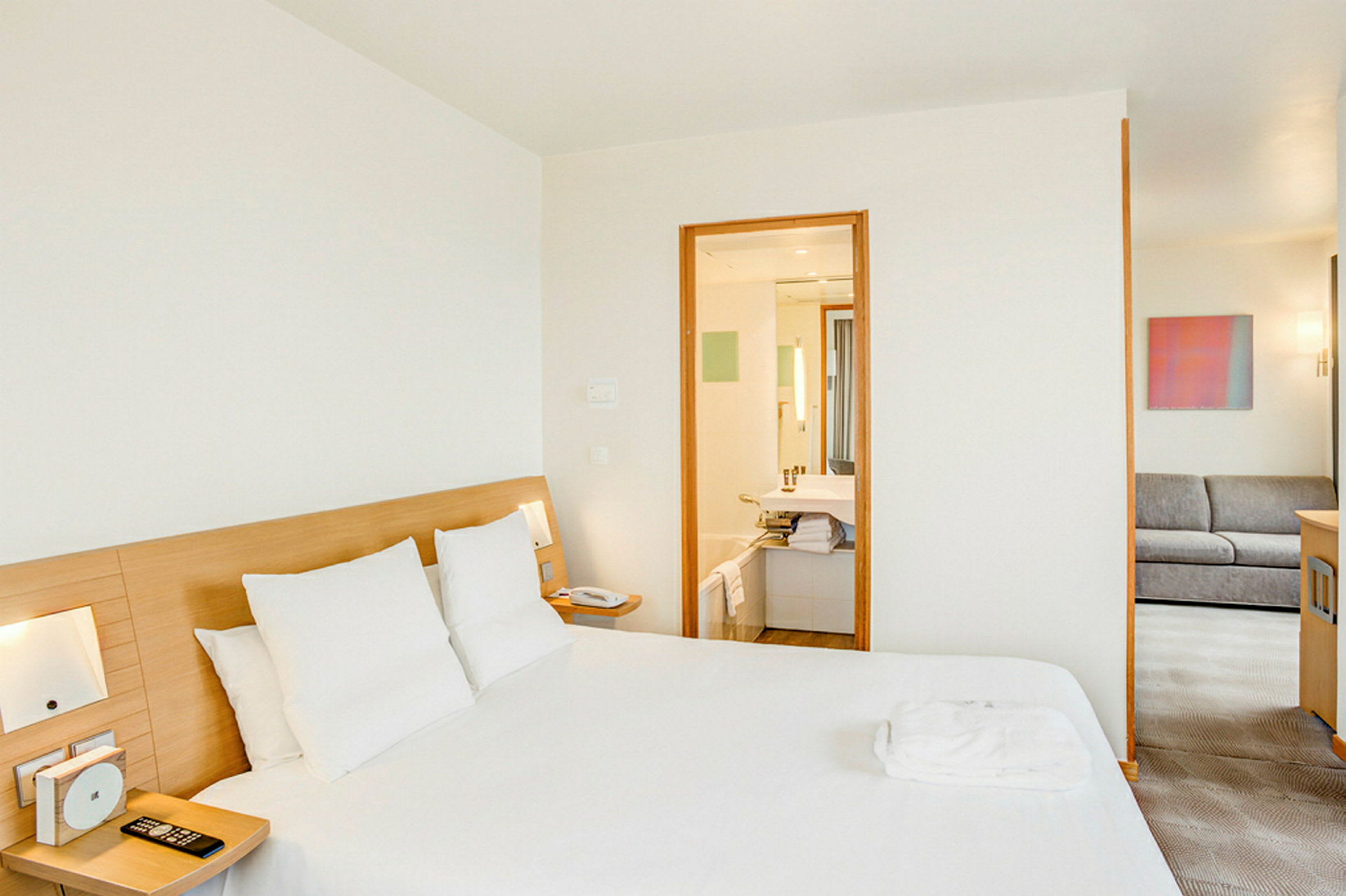 Et hotellrom med en dobbeltseng, bad og en sittegruppe. (AI-generert tekst)