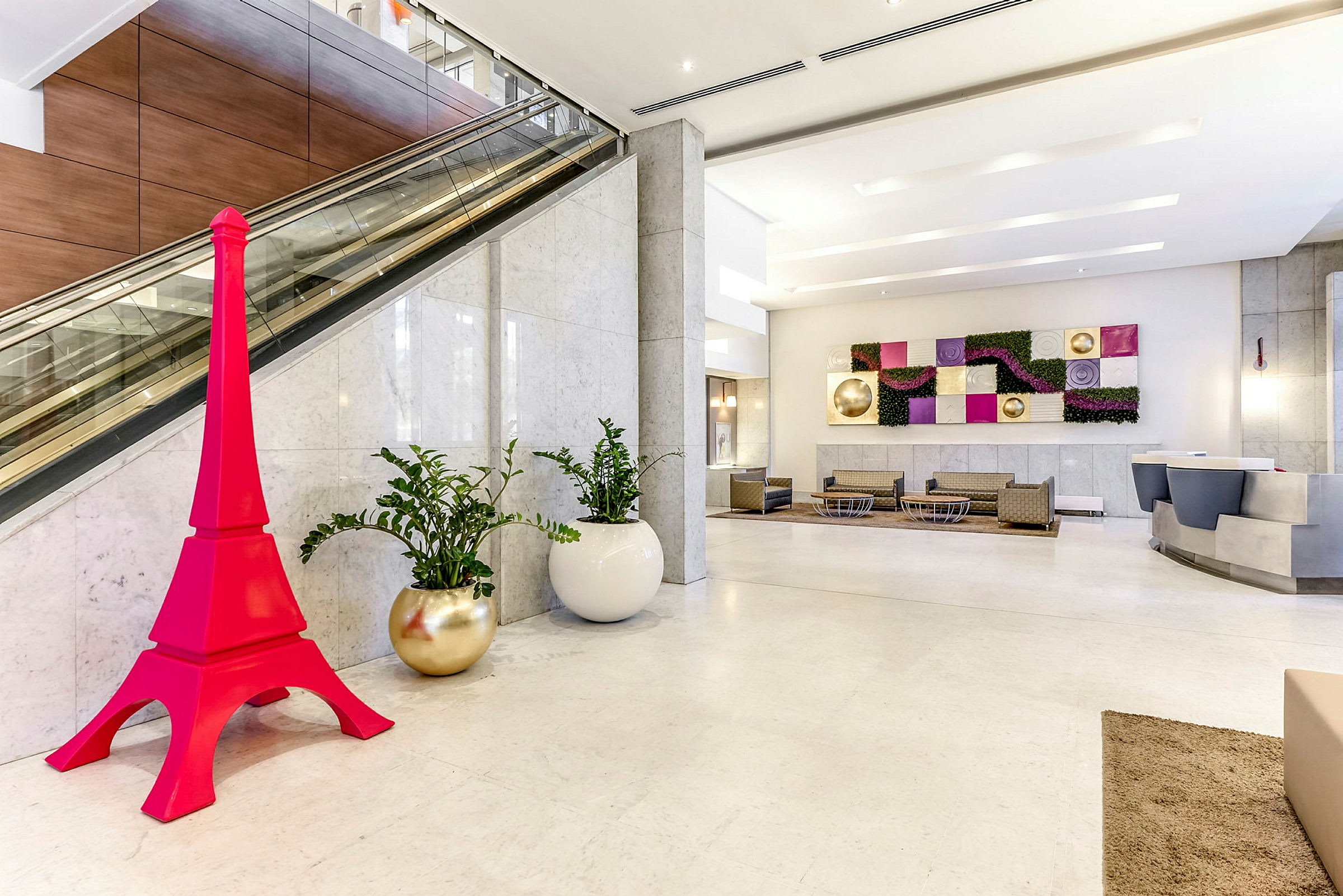 Hotellobby med moderne interiør, inkludert en rosa dekorasjon formet som et tårn. (AI-generert tekst)