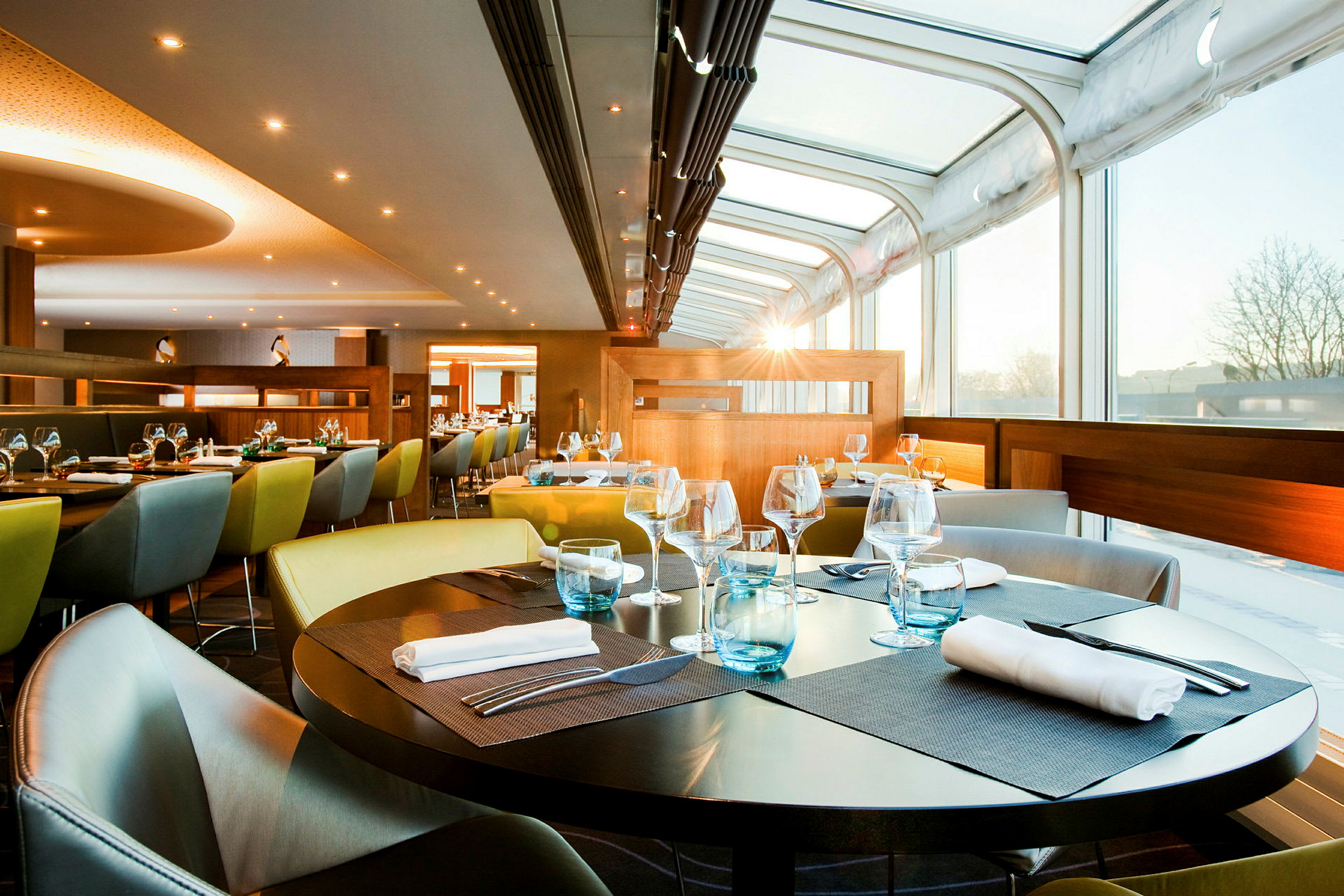 En moderne restaurant med glassvegger og dekkede bord med servietter og glass. (AI-generert tekst)