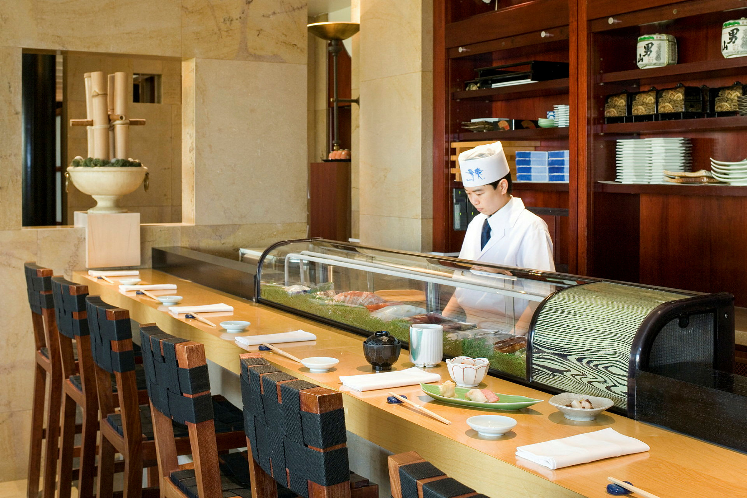 En sushi-bar med stoler ved en disk, forberedt med tallerkener og spisepinner. (AI-generert tekst)