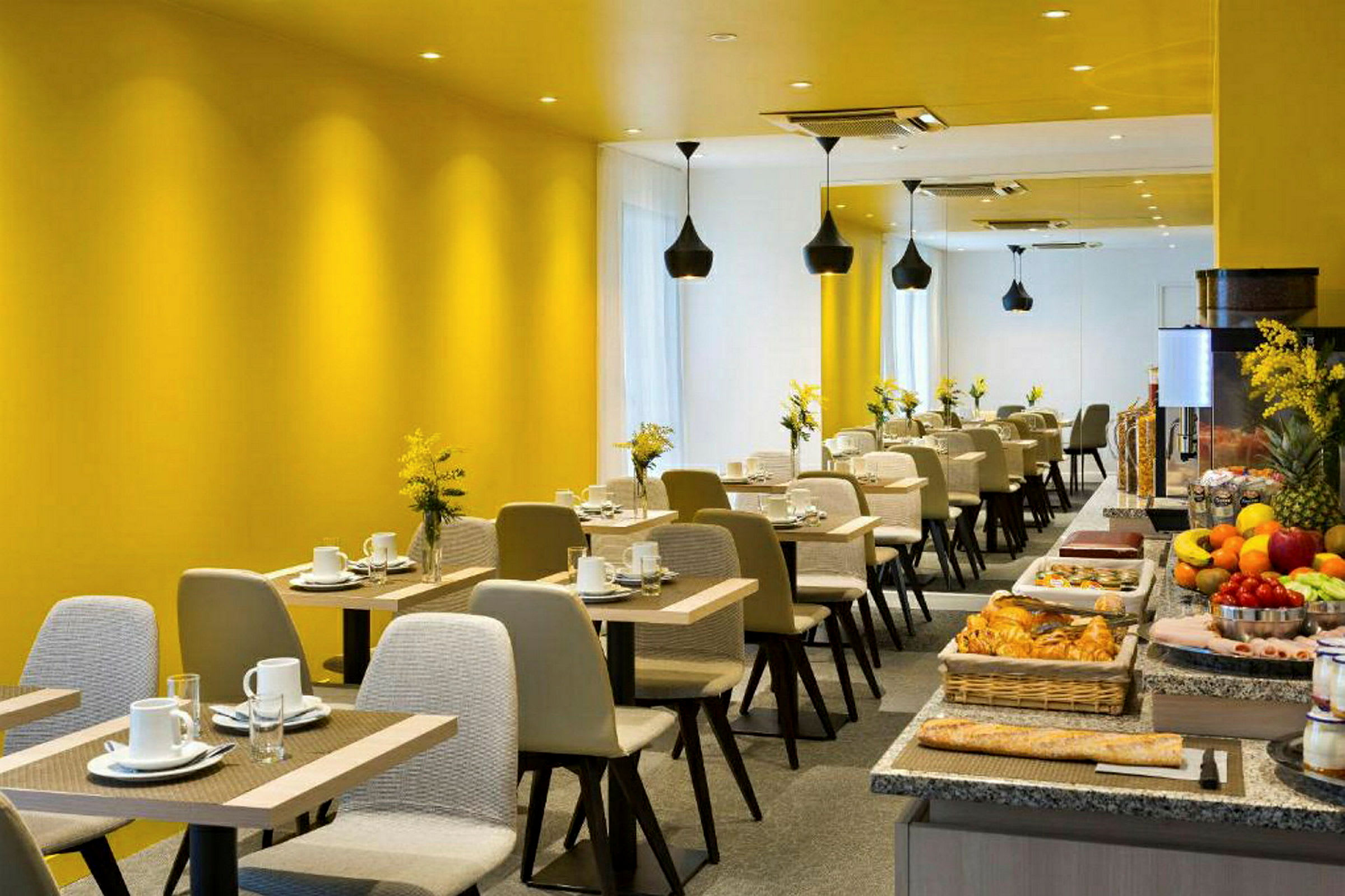 Et moderne restaurantområde med gule vegger, oppsatte bord og en buffé med ulike matvarer. (AI-generert tekst)