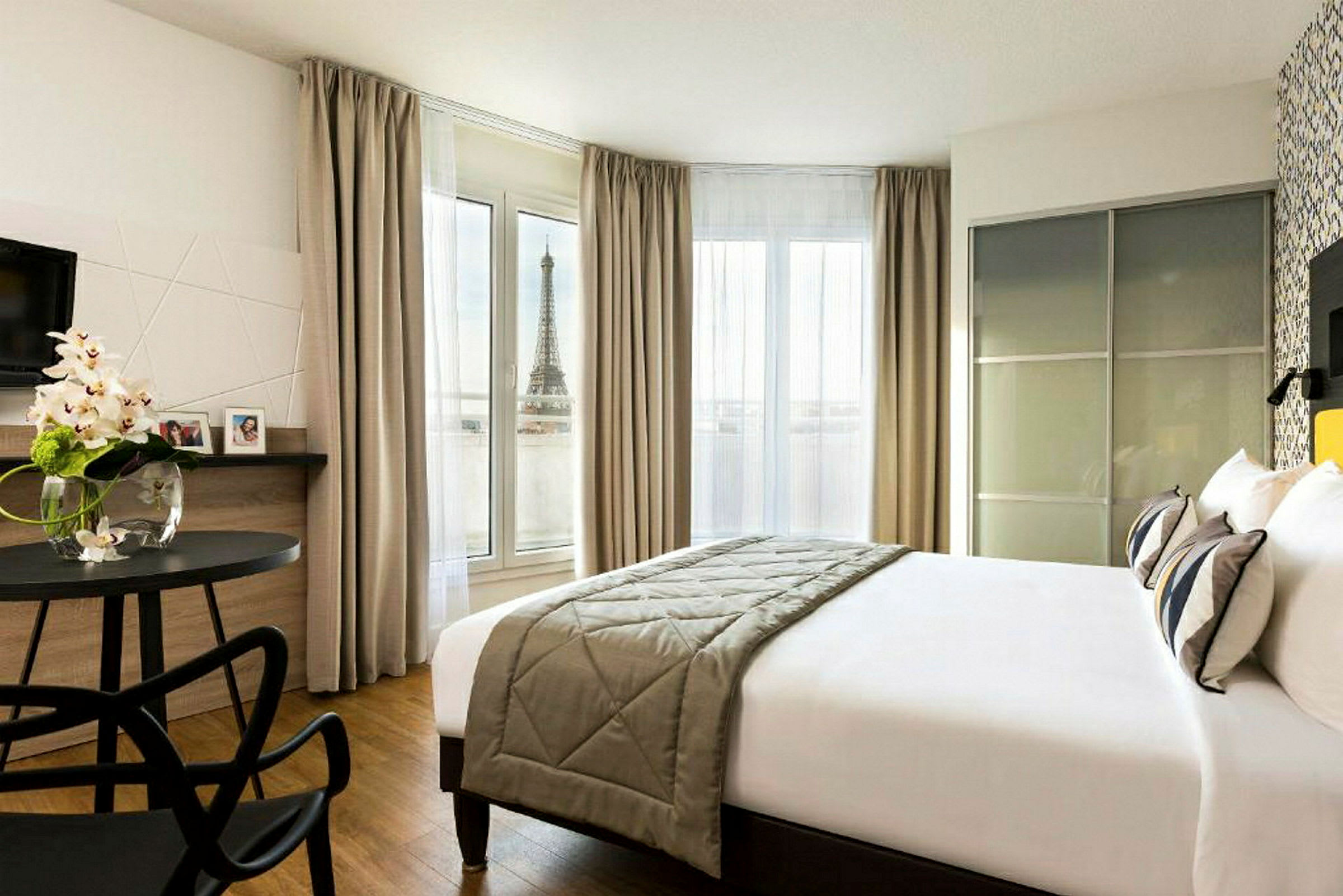 Et hotellrom med utsikt over Eiffeltårnet fra et vindu. (AI-generert tekst)