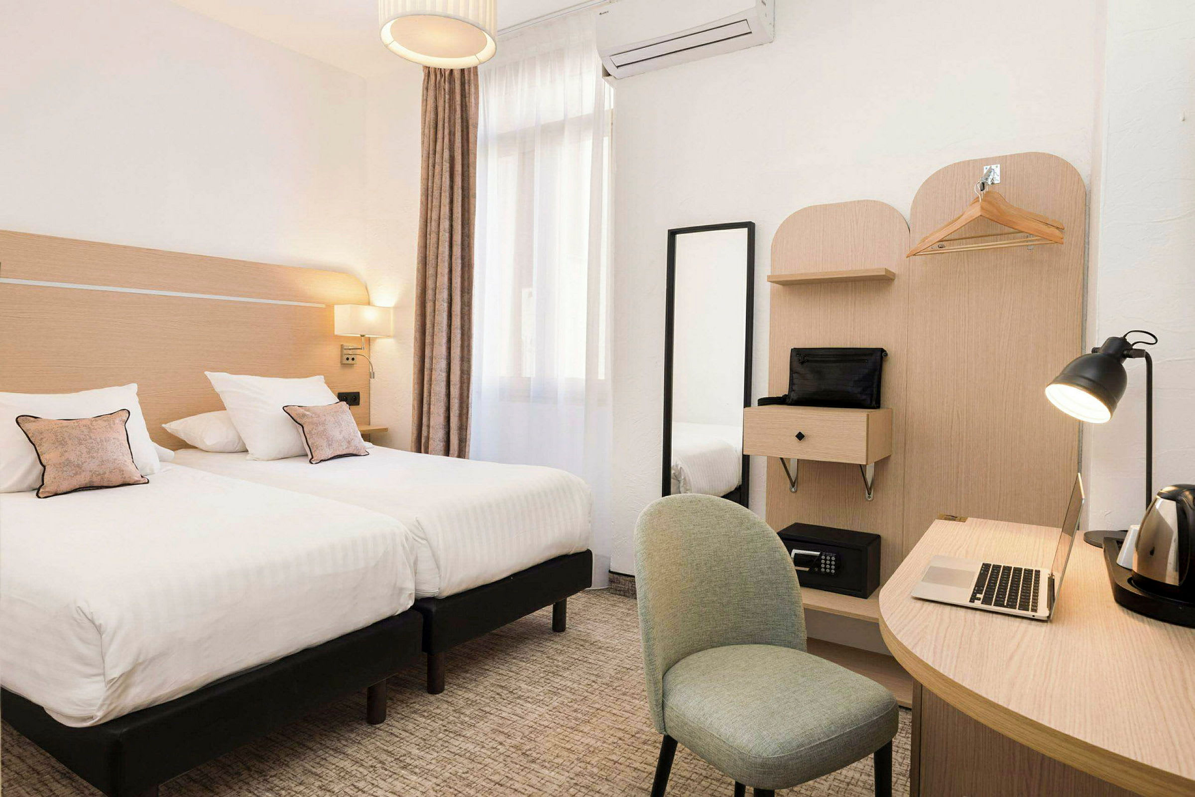Hotellrom med to enkeltsenger, et skrivebord, stol og garderobe. (AI-generert tekst)