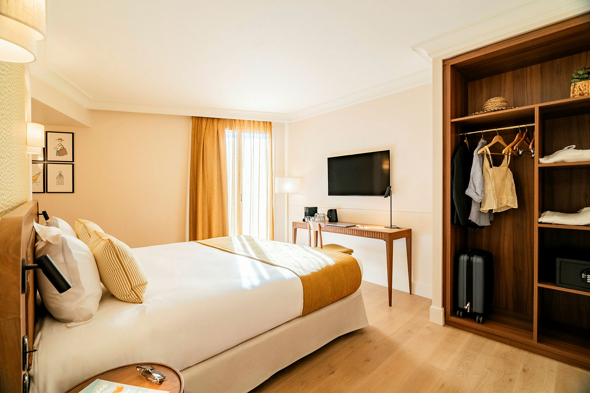 Et hotellrom med en dobbeltseng, en TV på veggen, et skrivebord og en garderobe med klær og bagasje. (AI-generert tekst)
