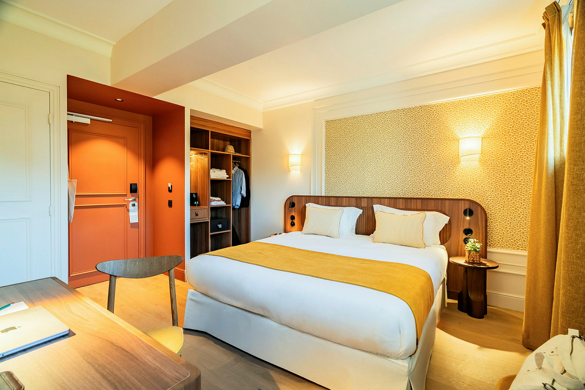 Et hotellrom med en stor dobbeltseng, et skrivebord og en garderobe. (AI-generert tekst)
