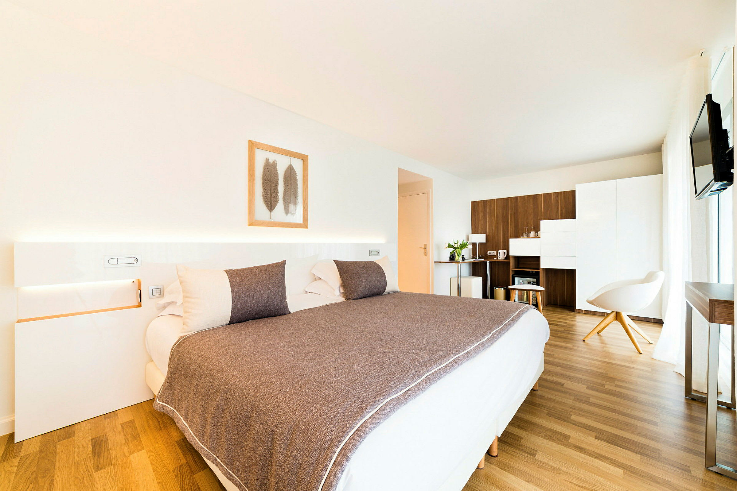 Et moderne hotellrom med en stor seng, minimalistisk innredning og tremøbler. (AI-generert tekst)