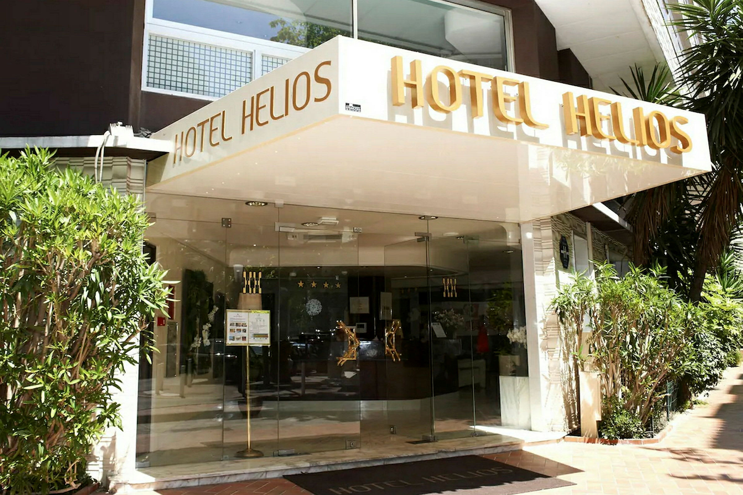 Inngangen til hotellet Hotel Helios med navnet skrevet over inngangen. (AI-generert tekst)
