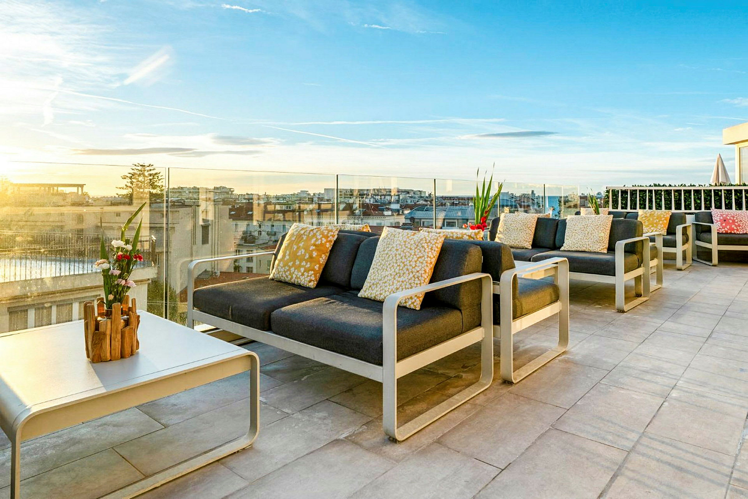 Møblert takterrasse med utsikt over byen og solnedgangen. (AI-generert tekst)