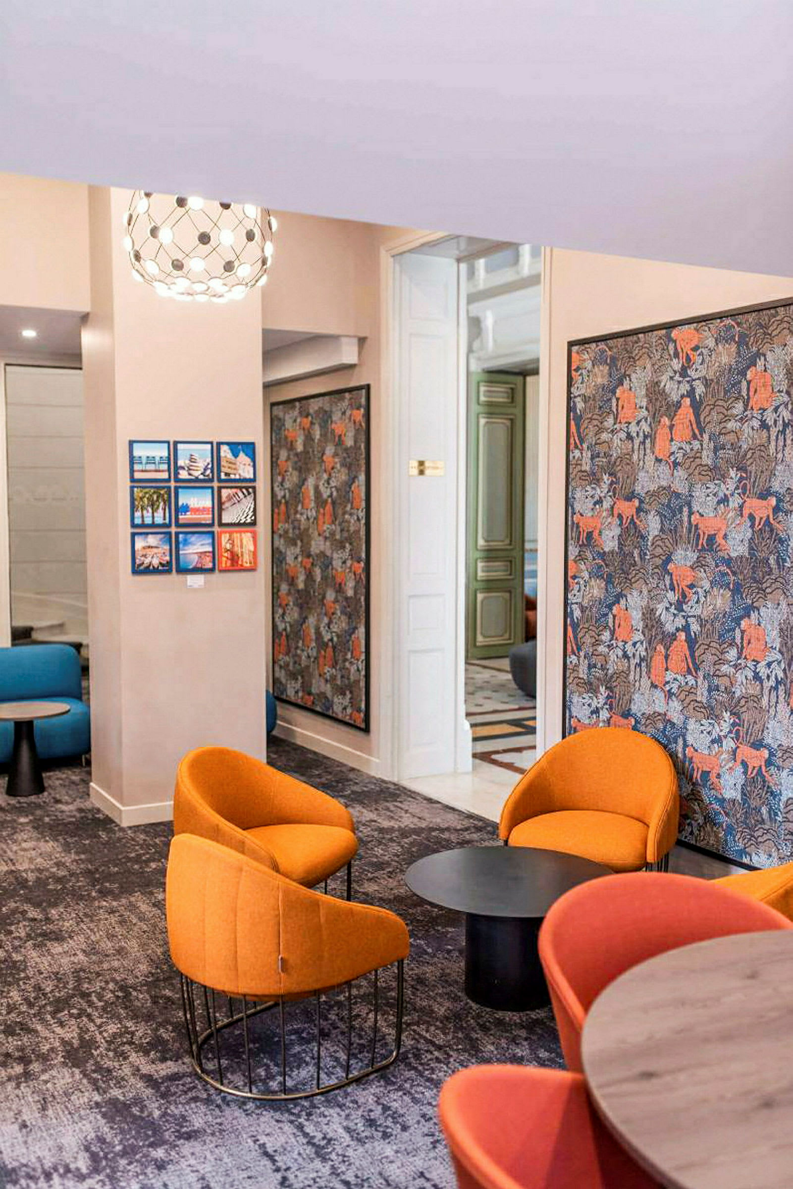 Et moderne innredet rom med flere sitteplasser, oransje og blå lenestoler og dekorative veggpaneler. (AI-generert tekst)