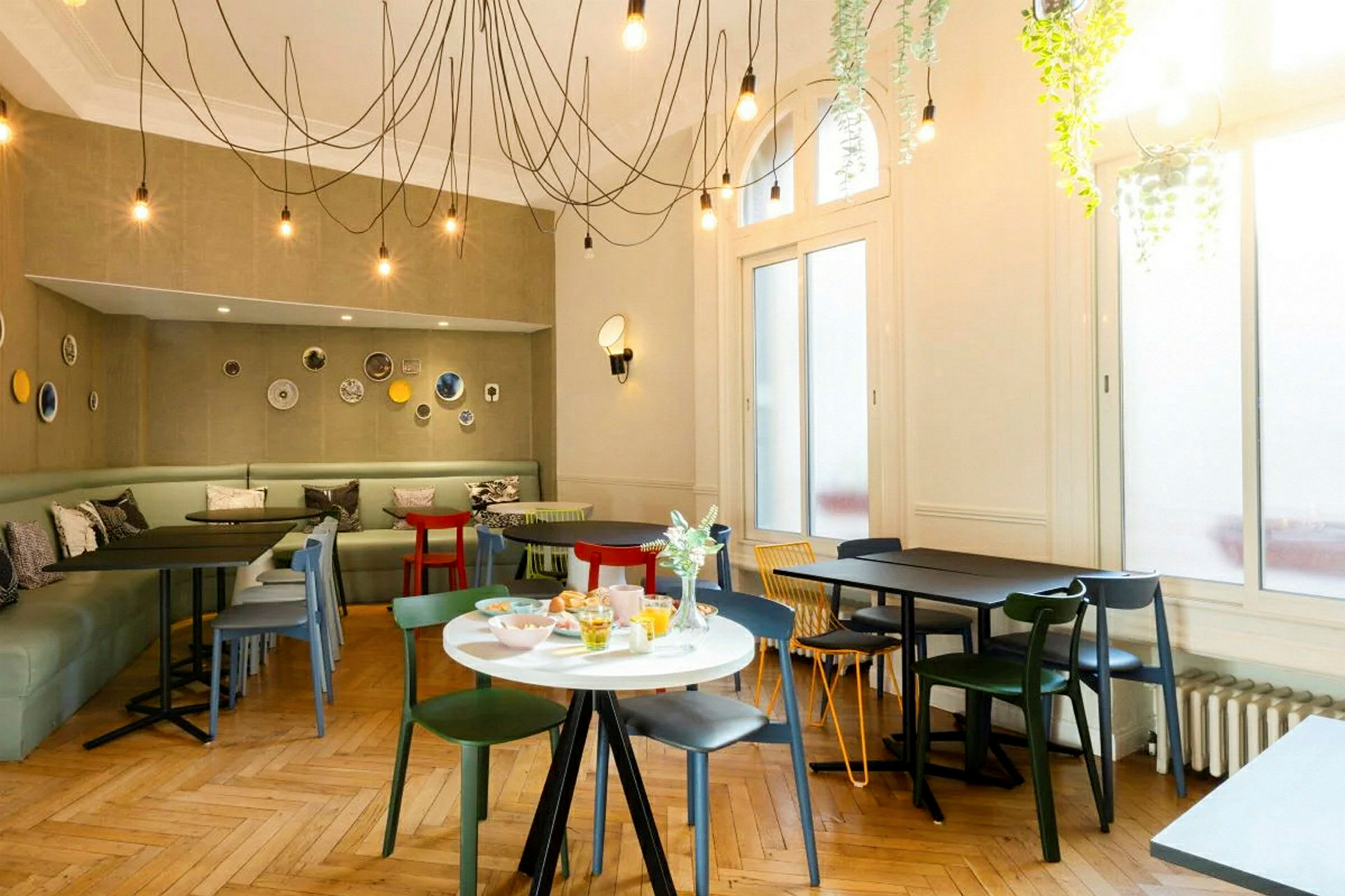 En moderne innredet kafé med fargerike stoler og bord samt dekorasjoner på veggene. (AI-generert tekst)