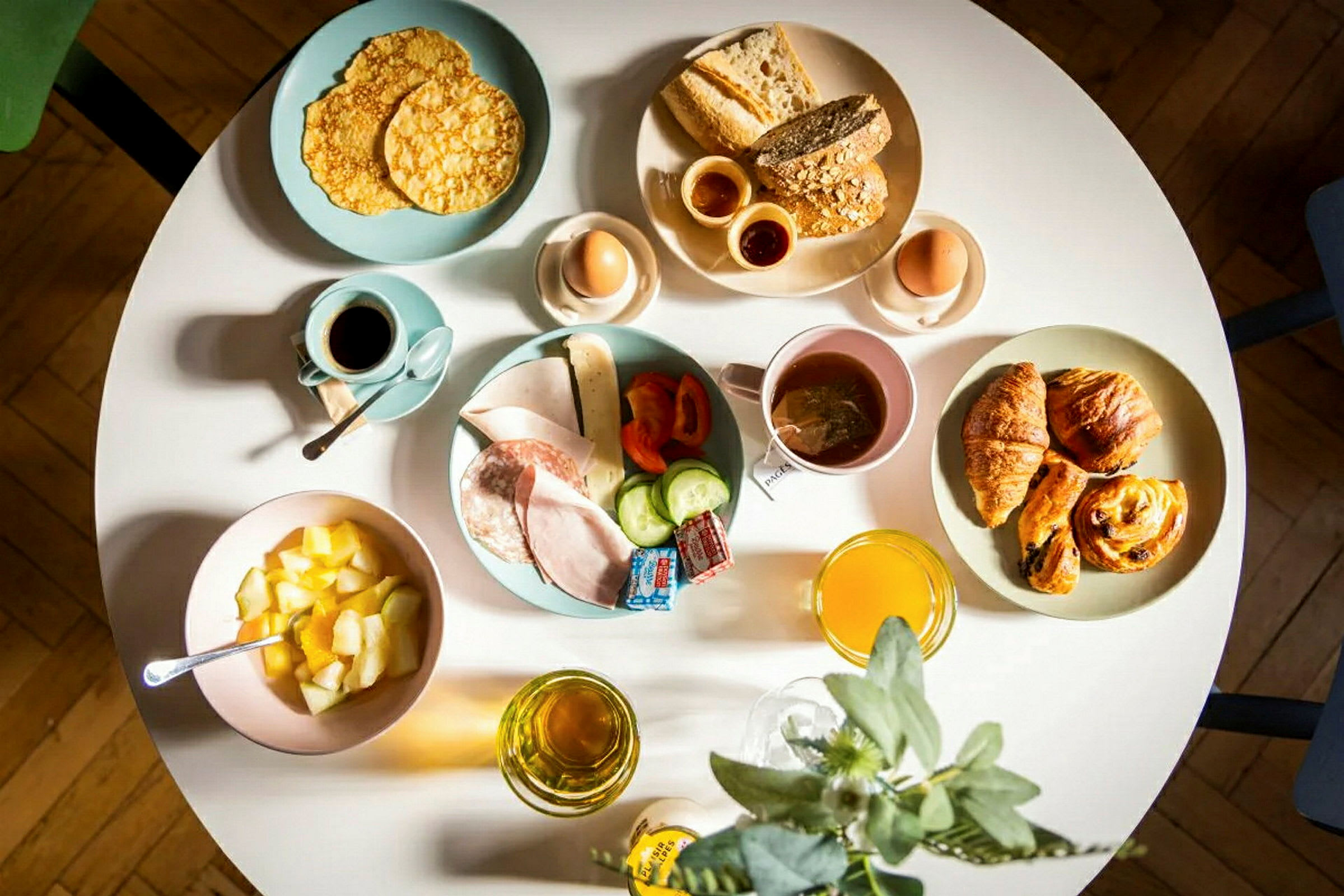 En frokostservering med brød, bakverk, egg, frukt, pålegg og drikke. (AI-generert tekst)