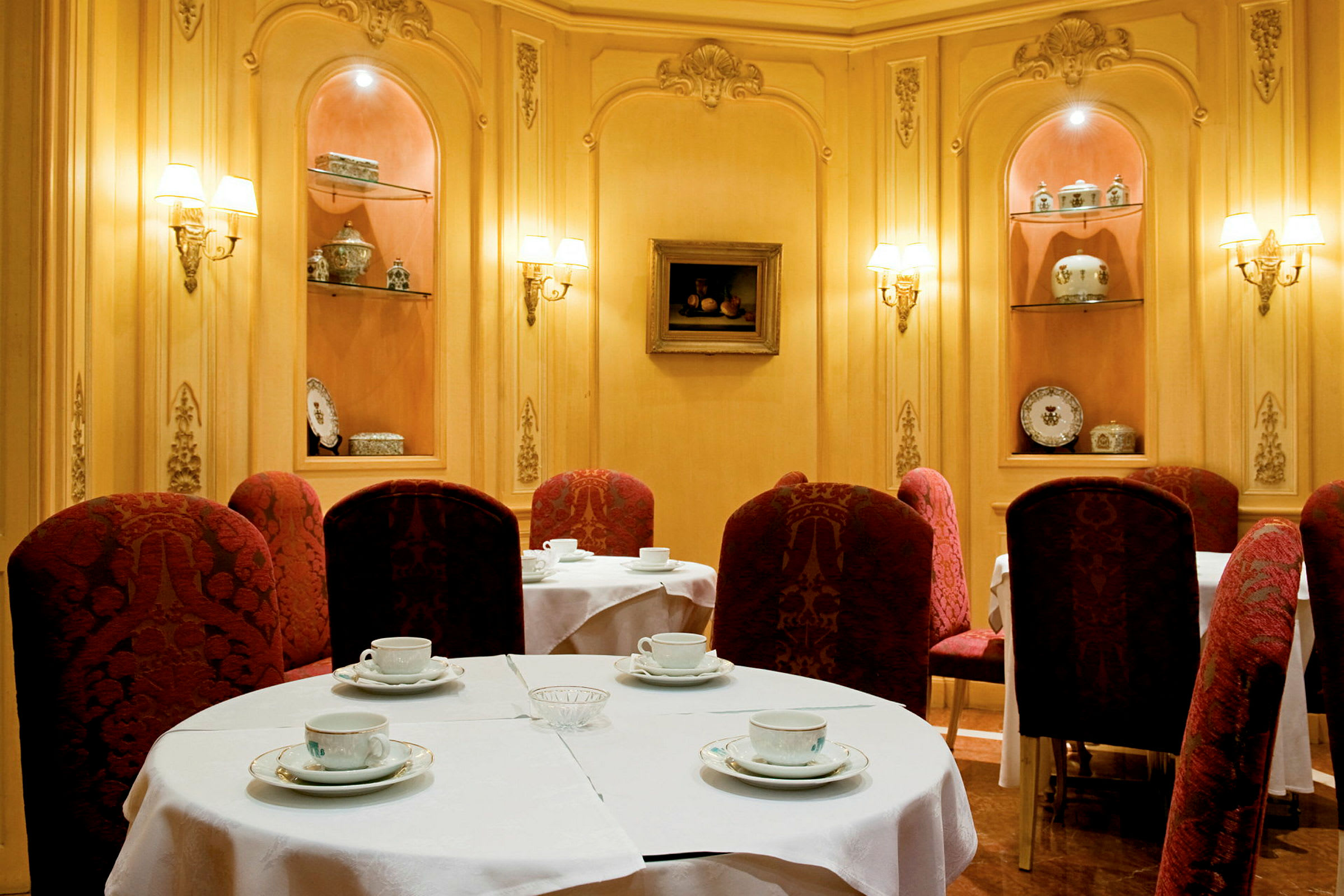 En elegant innredet kafé med bord dekket med hvite duker og røde stoler. (AI-generert tekst)