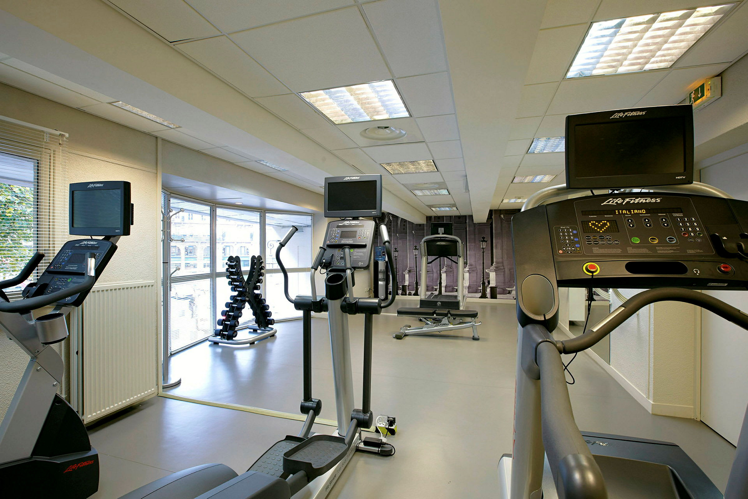 Et treningsstudio med treningsutstyr som tredemøller, elliptiske maskiner og manualer. (AI-generert tekst)