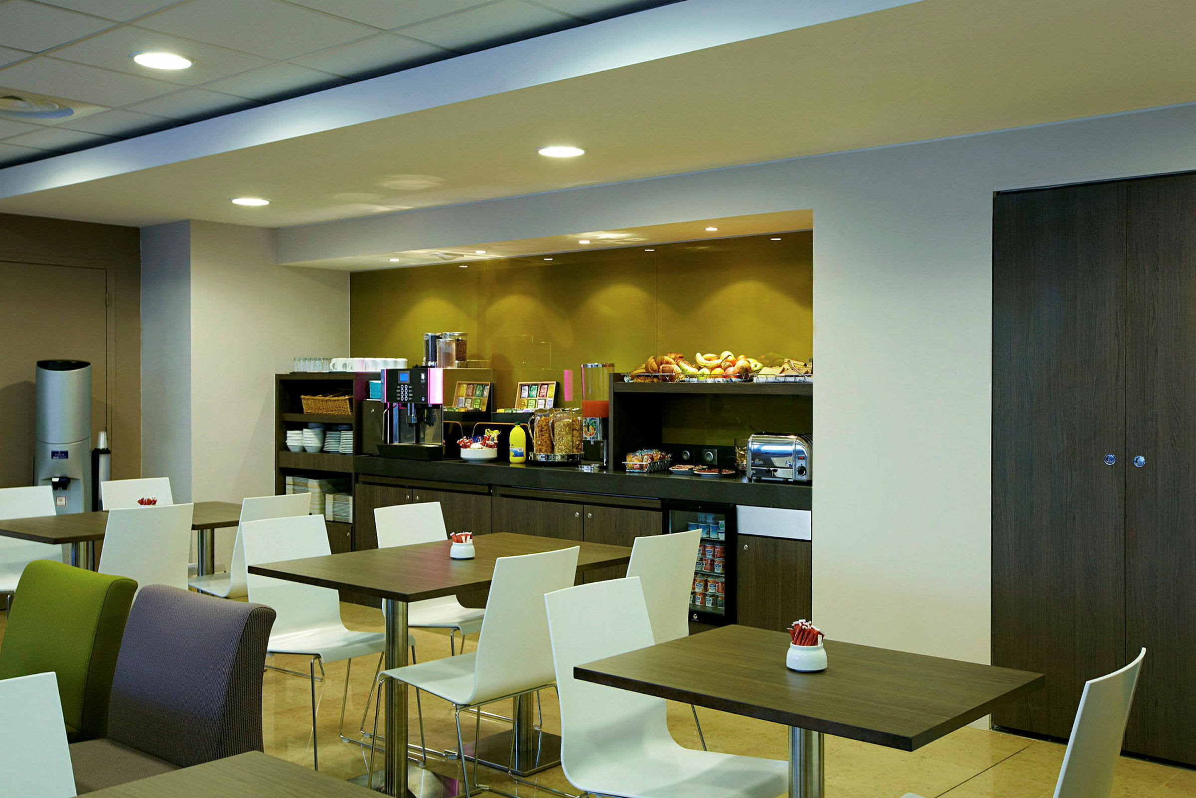 Frokostrom med bord og stoler og en buffet med forskjellige matvarer. (AI-generert tekst)