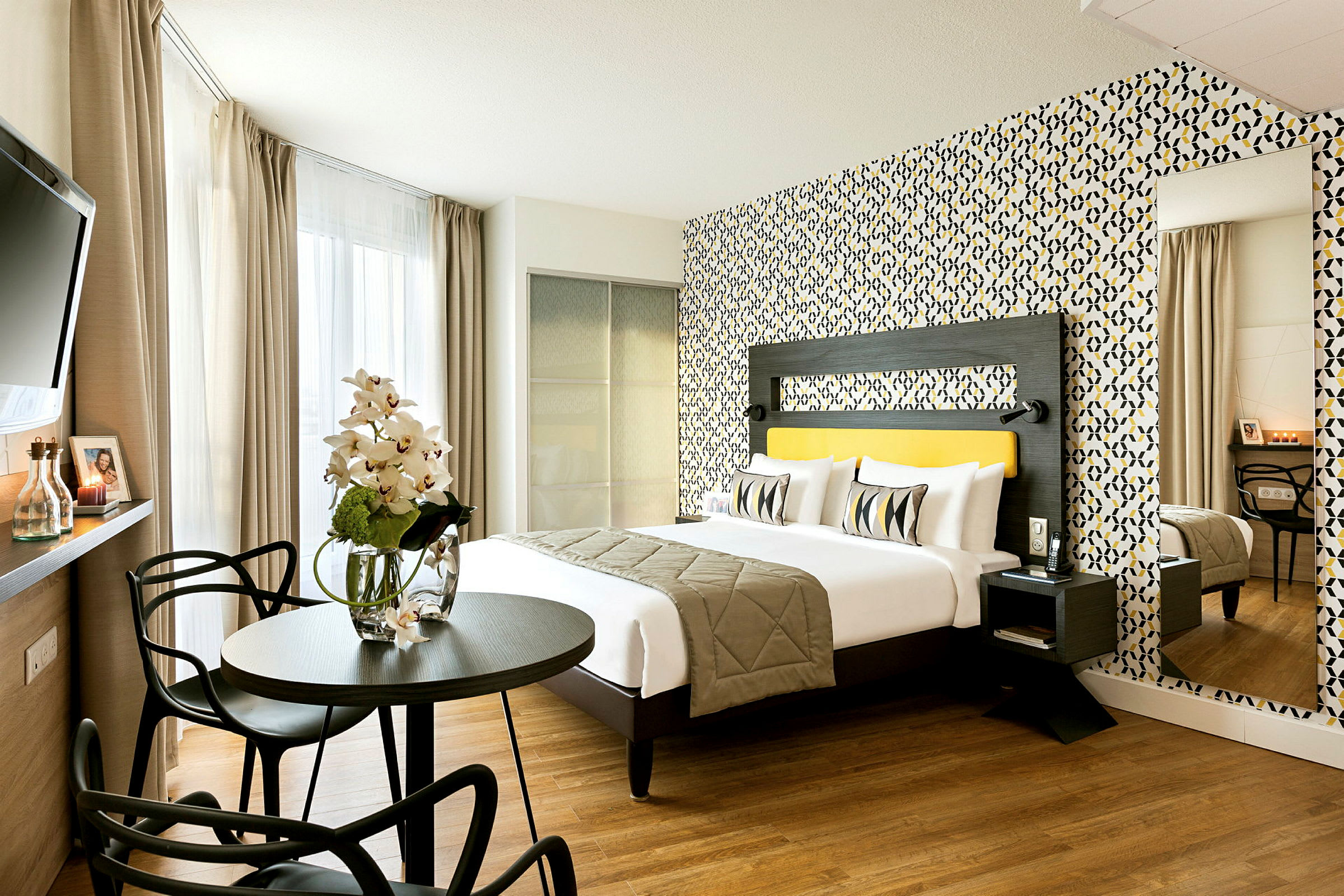 Et moderne hotellrom med en dobbeltseng, fargerikt tapet og sittegruppe. (AI-generert tekst)