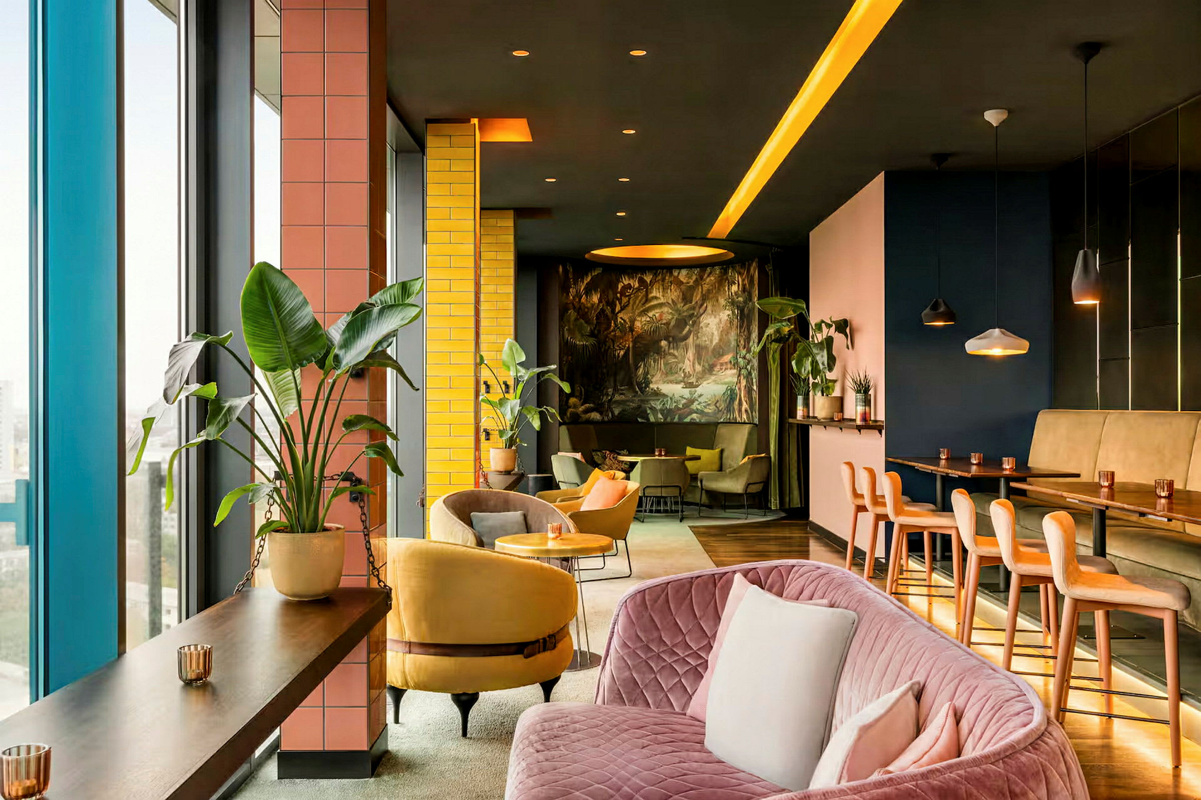 Interiør av en moderne og fargerik loungemiljø med planter, sofaer og stoler samt et høyt bordområde. (AI-generert tekst)
