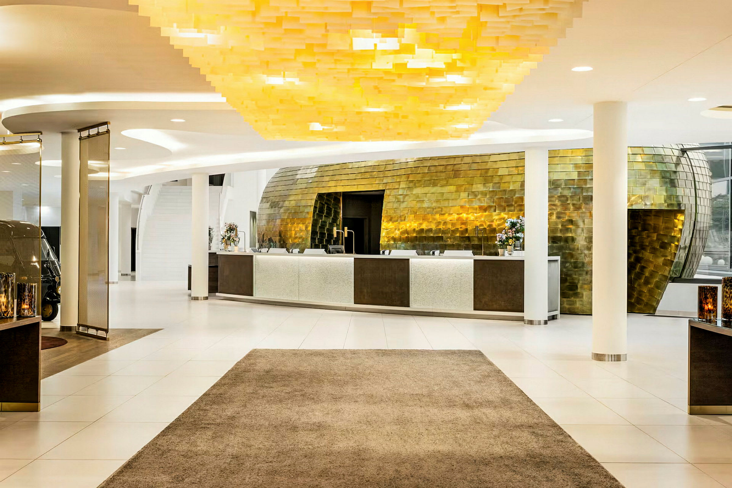 Resepsjon i en moderne hotellobby med et stilig gyllent interiør og lys innredning. (AI-generert tekst)