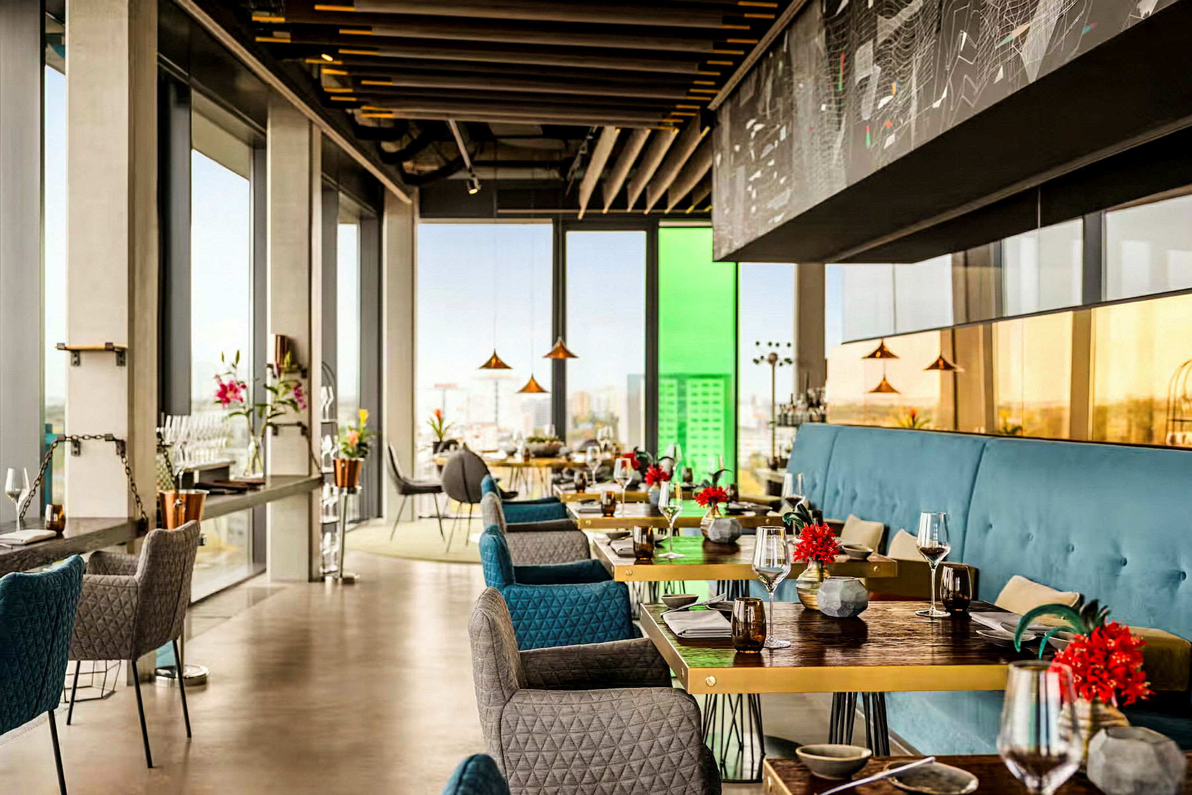 En elegant, moderne restaurant med store vinduer som slipper inn mye lys og tilbyr utsikt over byen. Bordene er dekorert med blomster. (AI-generert tekst)