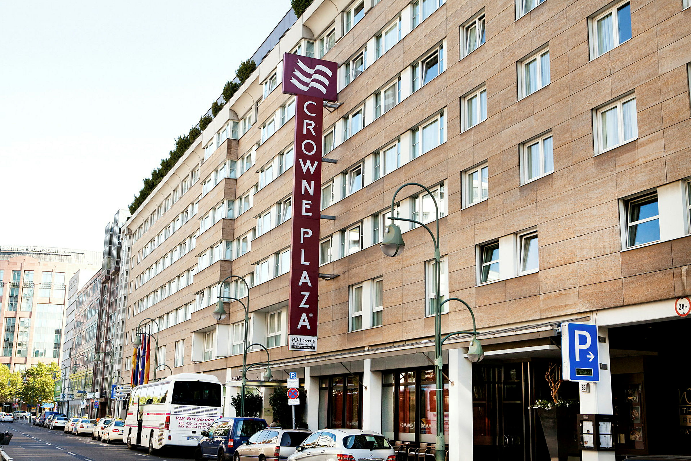 Crowne Plaza-hotellet bygning med parkeringsskilt og buss foran. (AI-generert tekst)