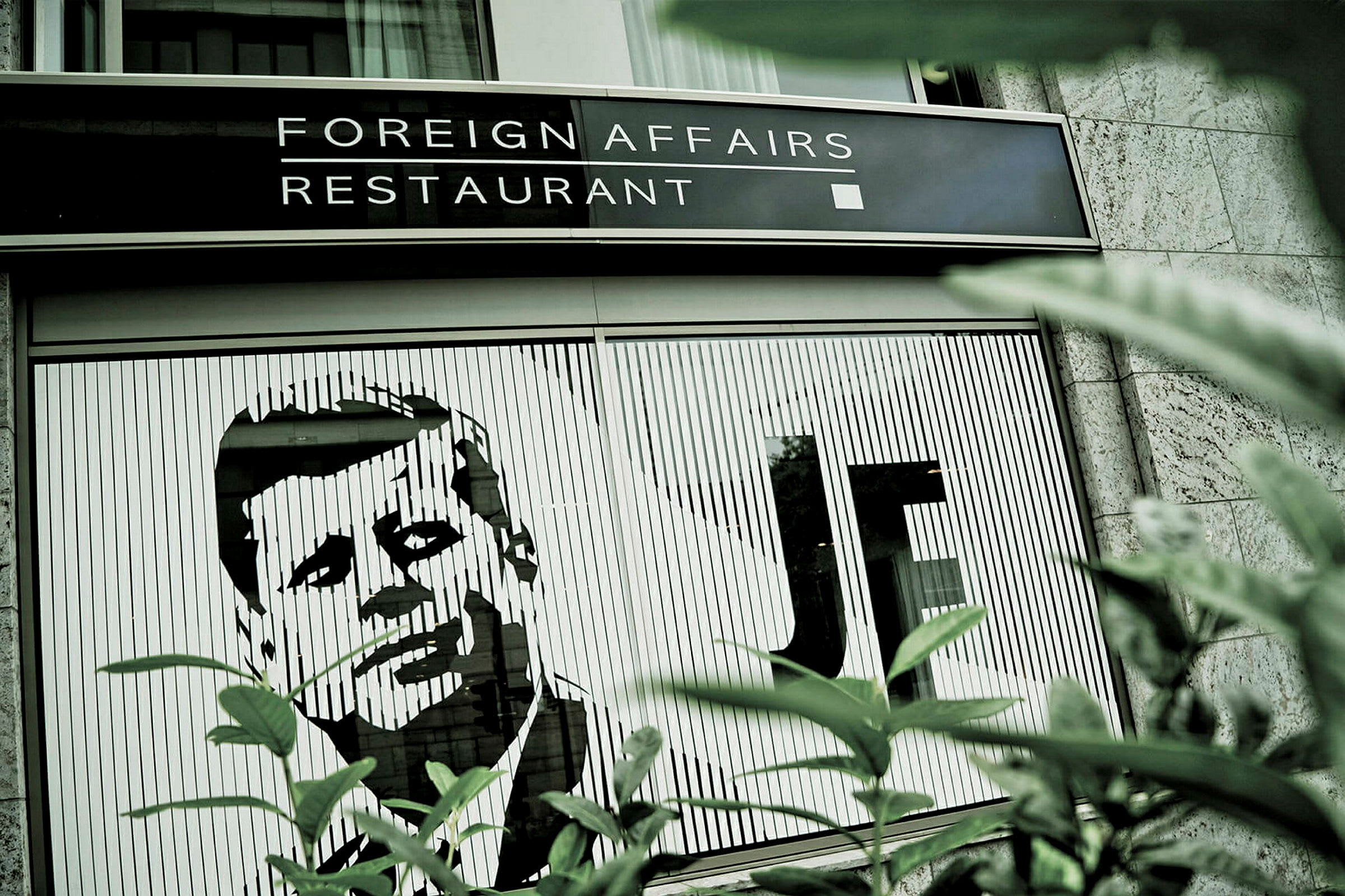 Bilde av en restaurant med navnet 'Foreign Affairs Restaurant' og en illustrasjon av en mann på bygningens fasade. (AI-generert tekst)