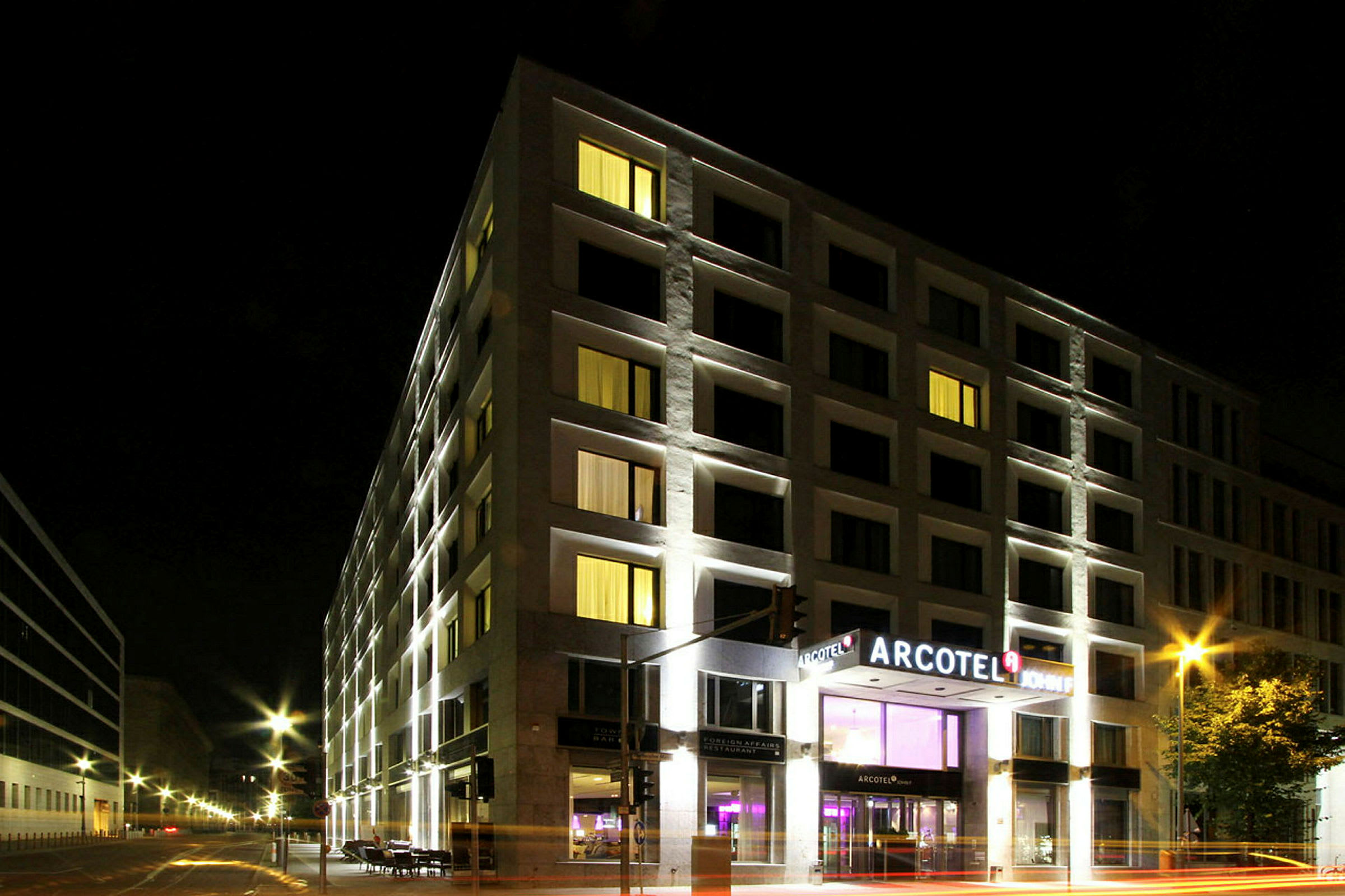 Et hotell opplyst om kvelden med Arcotel-skiltet ved inngangen. (AI-generert tekst)