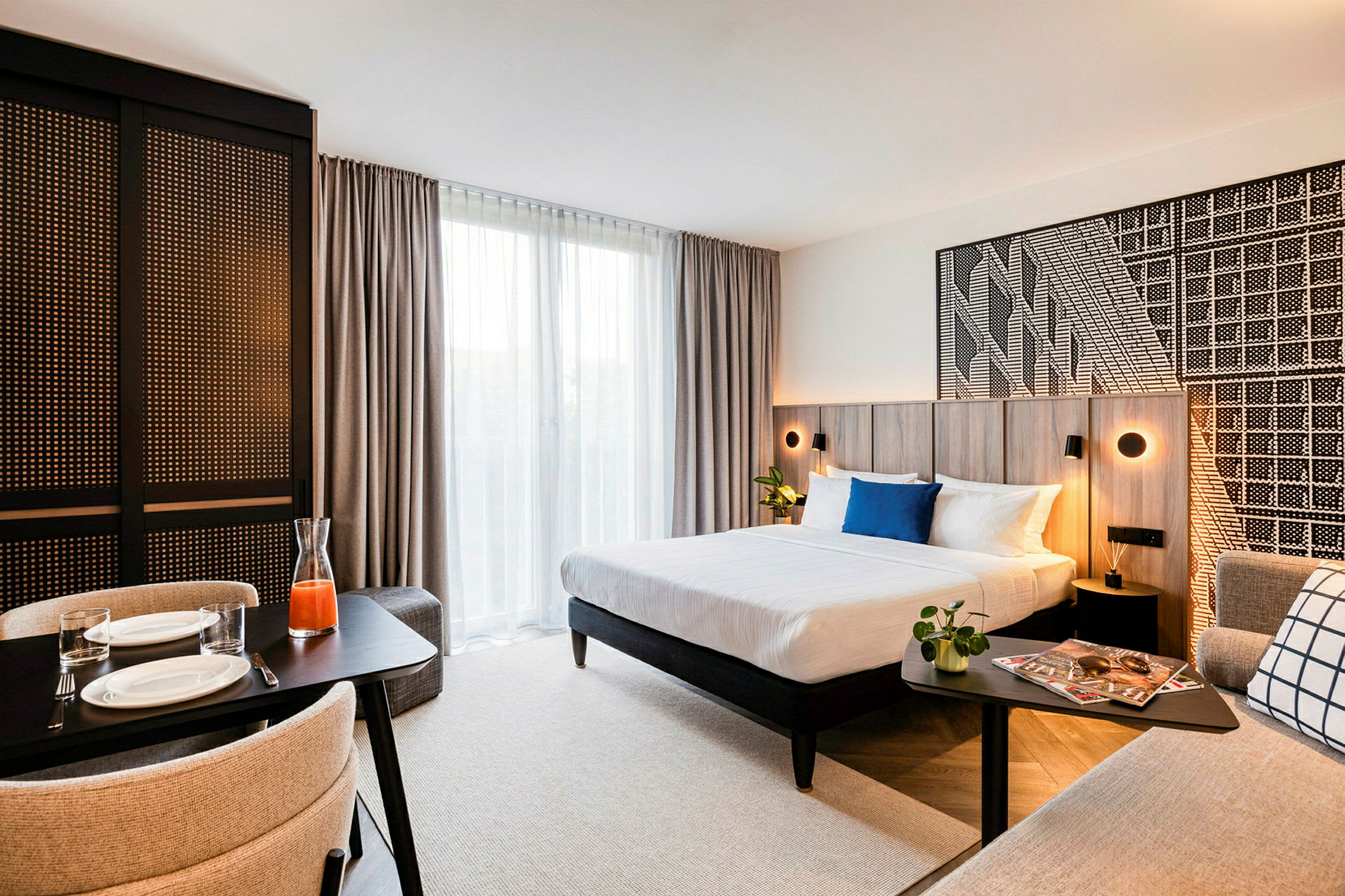 Et moderne hotellrom med dobbeltseng, småbord og spiseplass. (AI-generert tekst)