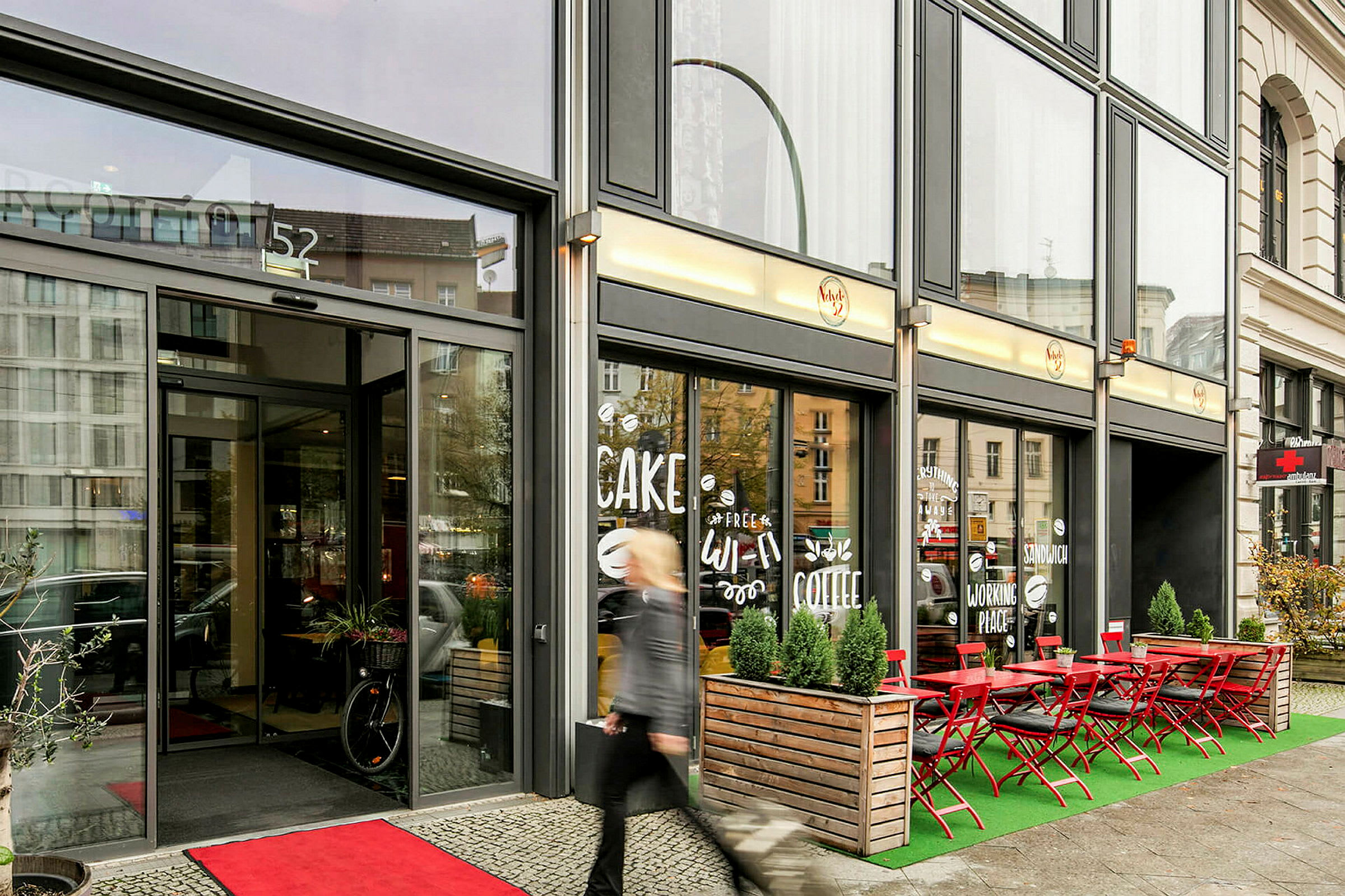 Inngangen til en kafébygning med uteservering og skilt i vinduet. (AI-generert tekst)