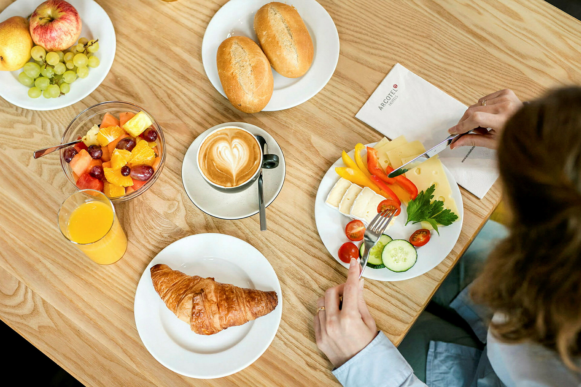 En frokost med kaffe, croissant, fruktsalat, ost, grønnsaker og brød. (AI-generert tekst)