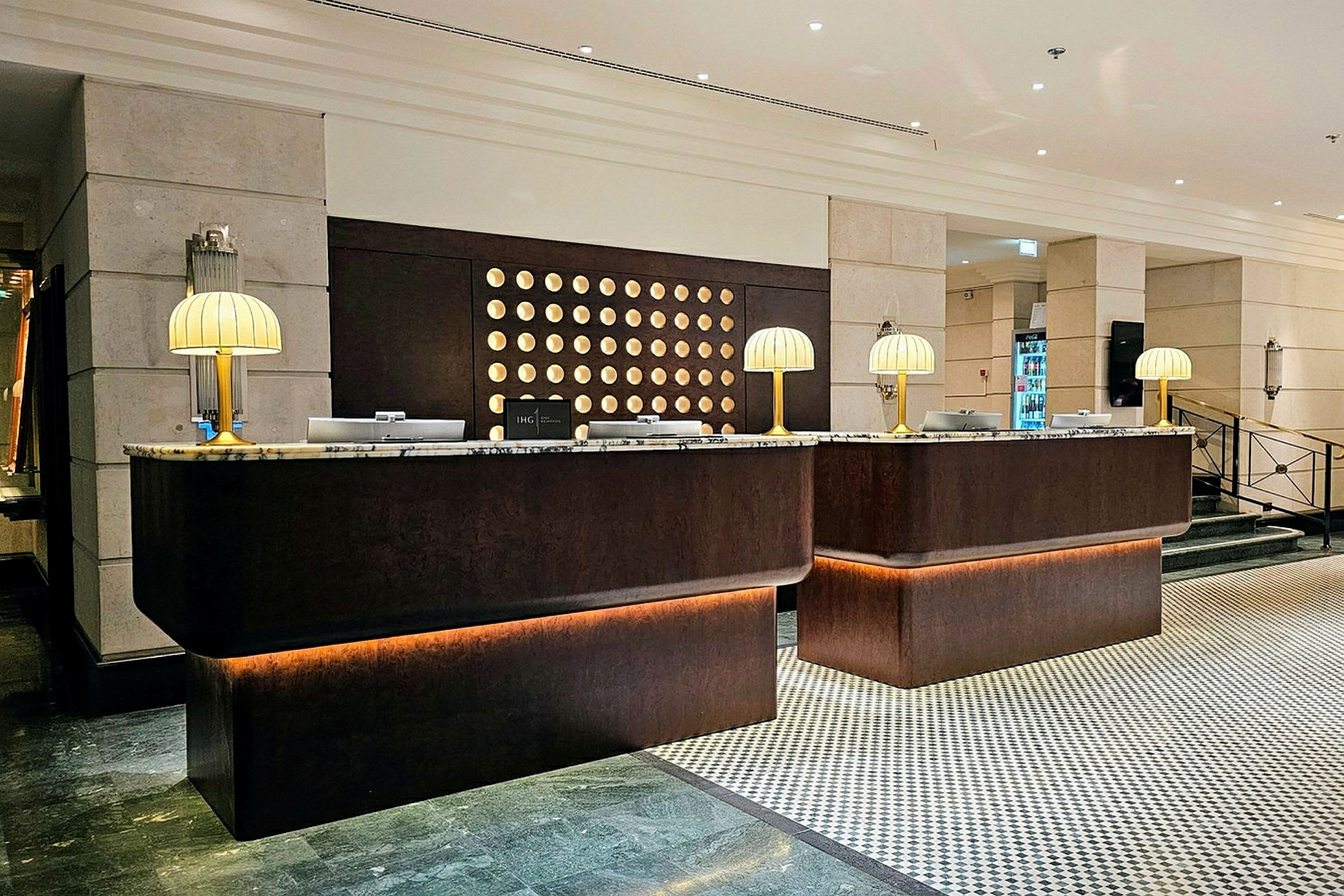 En resepsjonsdisk i en hotellobby, med marmortopper og bordlamper. (AI-generert tekst)