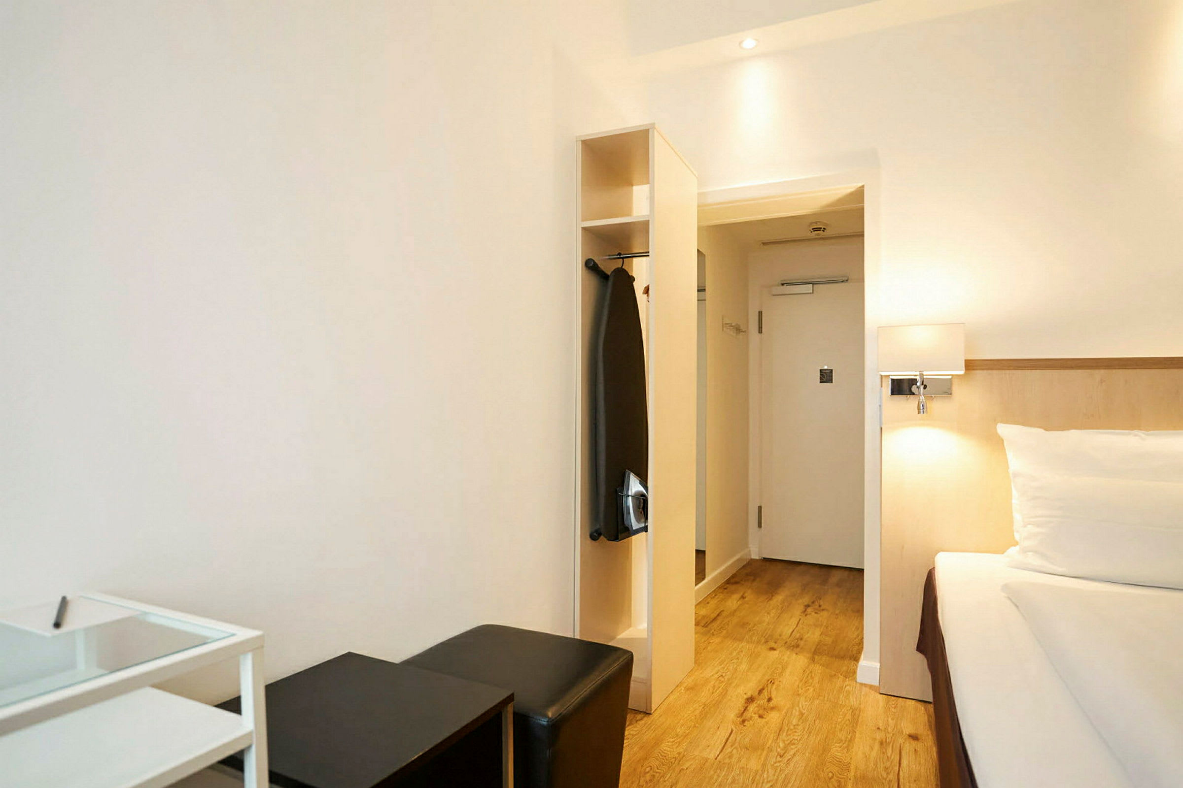 Et hotellrom med seng, sittemøbler og garderobe. (AI-generert tekst)