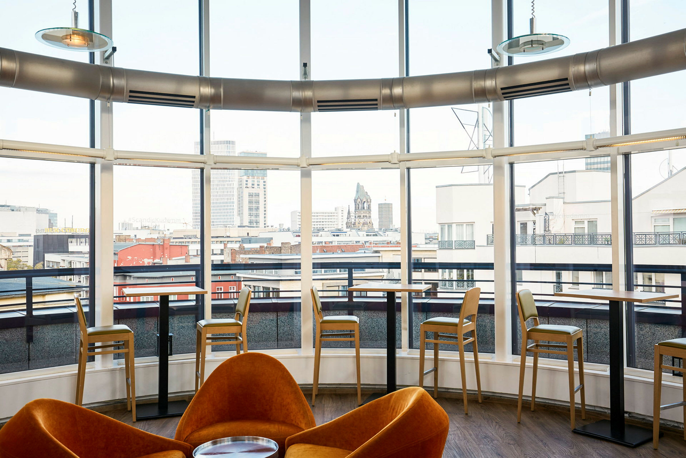 Innendørs utsikt over en moderne kafé med store vinduer mot byen. (AI-generert tekst)