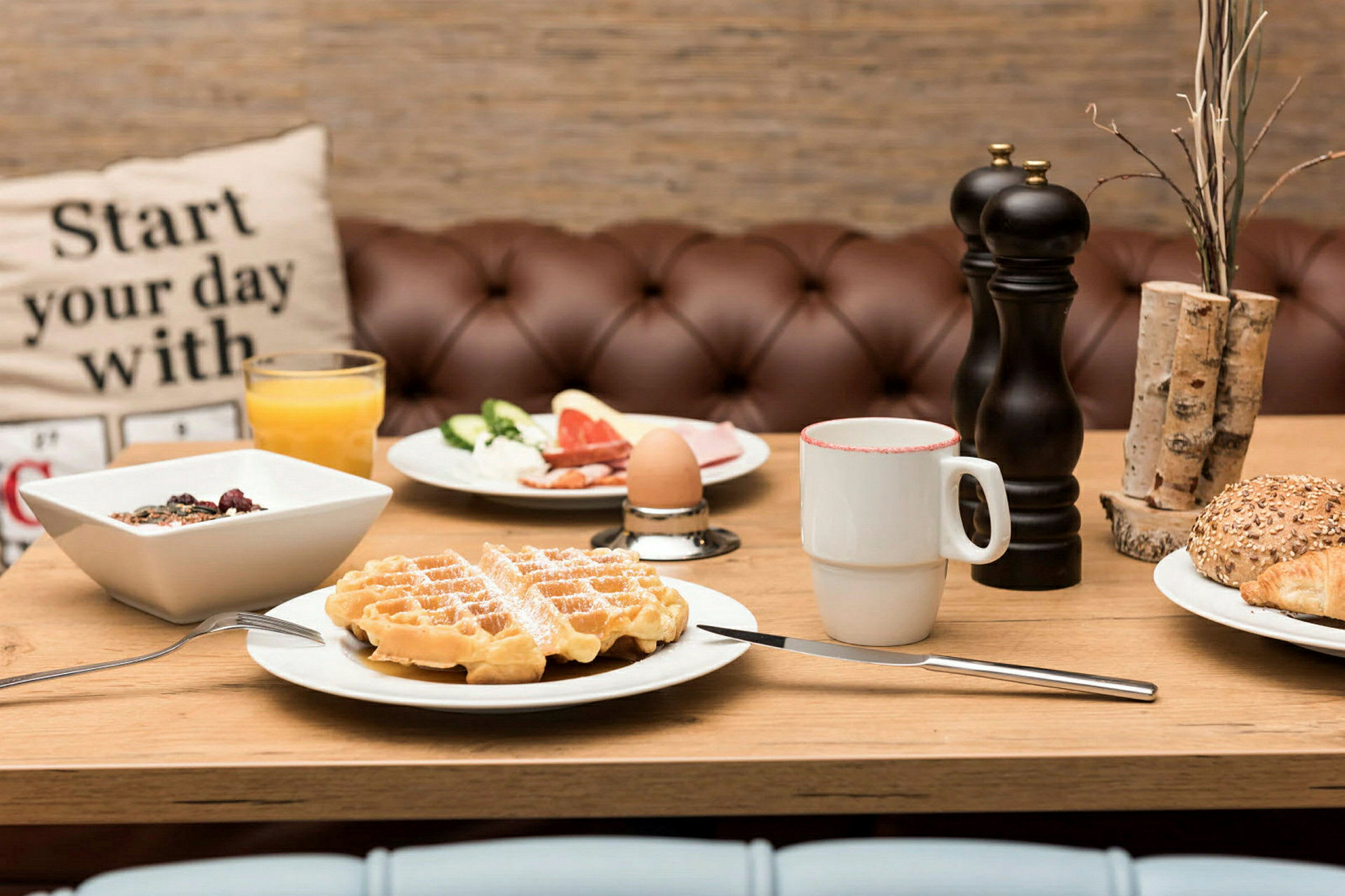 En frokostservering med vafler, brød, yoghurt og kaffe. (AI-generert tekst)