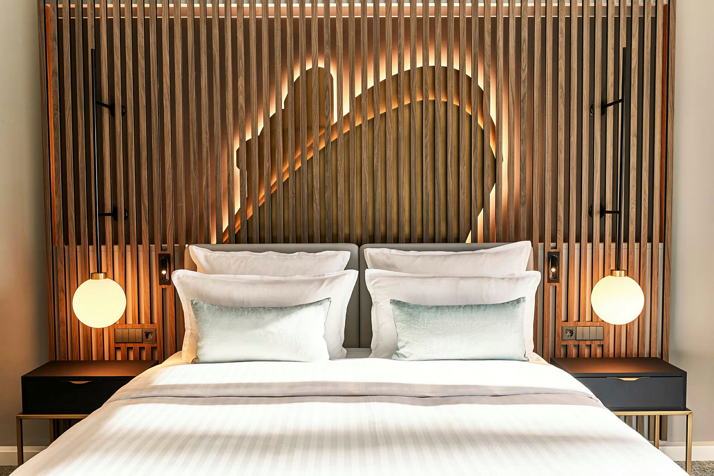 En moderne hotellseng med hvitt sengetøy og treinnslag bak på hodegavlen, opplyst med dekorativ bakgrunnsbelysning. (AI-generert tekst)