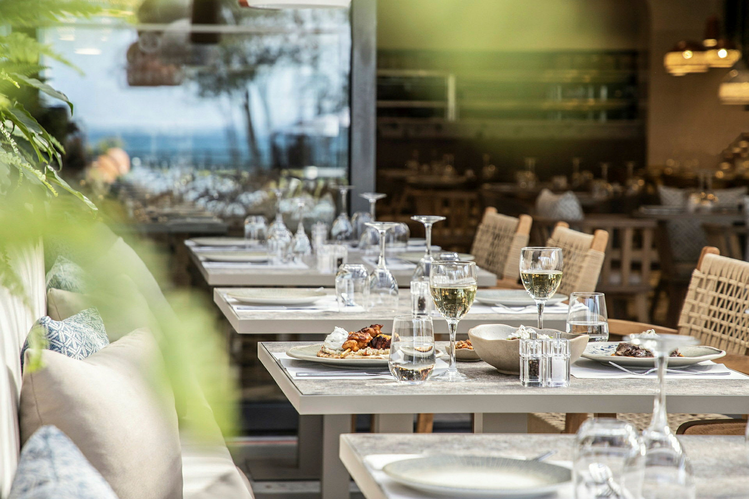 Bilde av oppdekkede bord på en restaurant med tallerkener, glass og stoler. (AI-generert tekst)