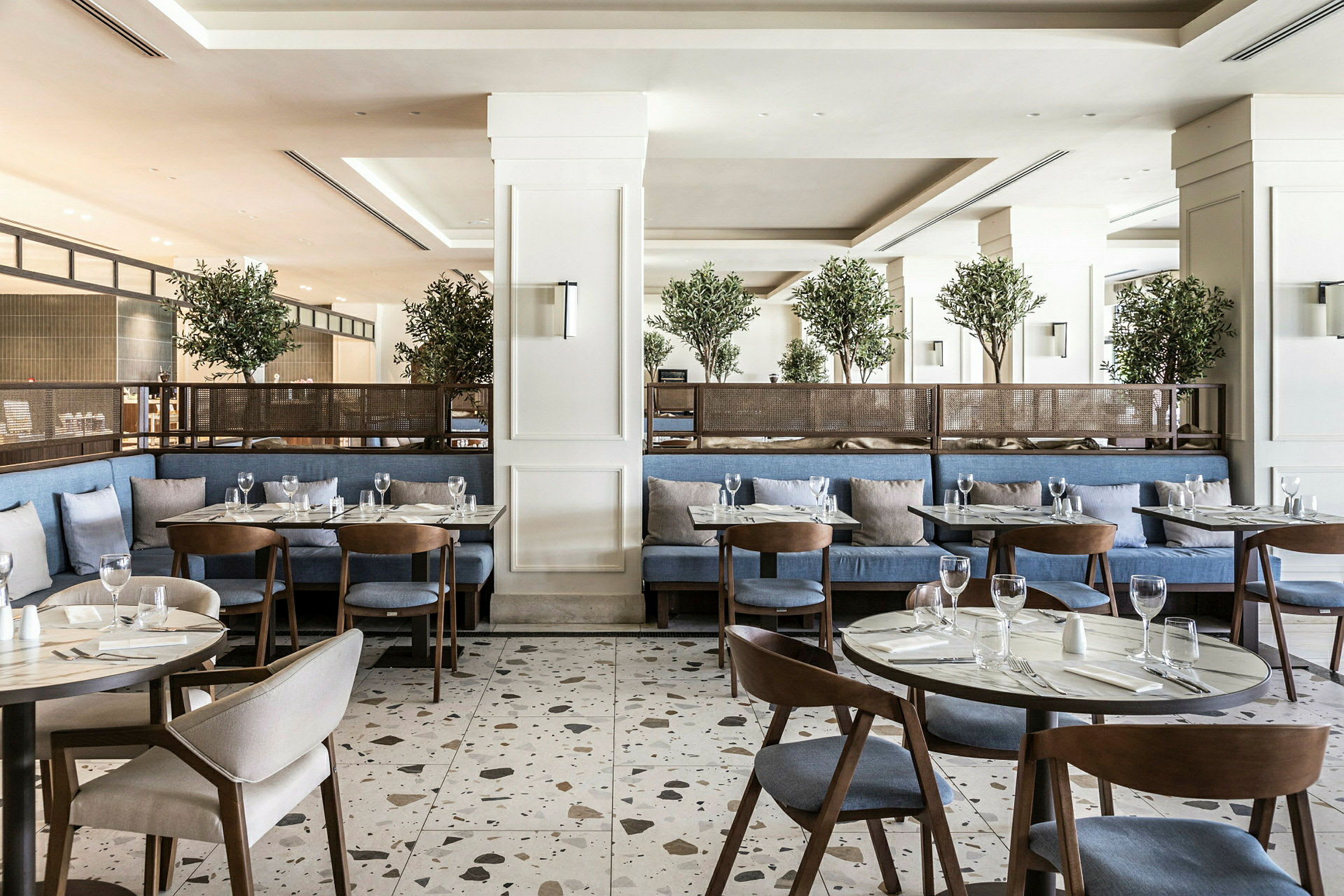 En moderne restaurant med blå sitteplasser, trebord og grønne planter som dekorasjon. (AI-generert tekst)