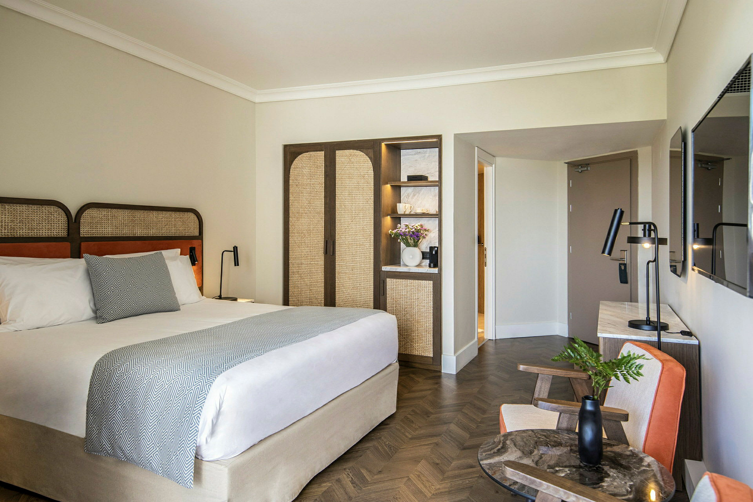 Et moderne hotellrom med en dobbeltseng, et klesskap med innebygde hyller og et bord med stoler. (AI-generert tekst)