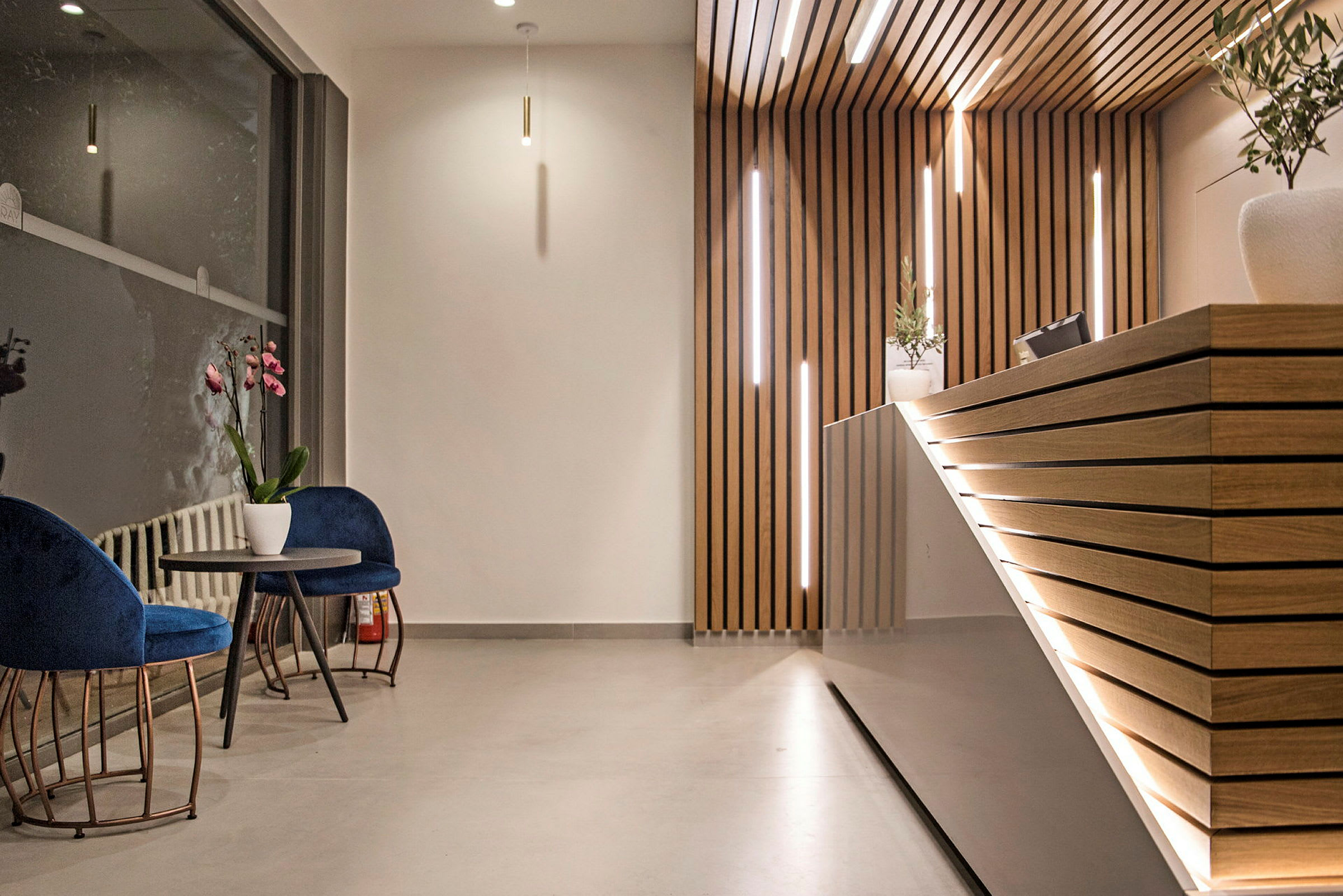 Bilde av et moderne resepsjonsområde med trebekledde vegg- og diskdetaljer samt to stoler med et bord ved siden av et stort vindu. (AI-generert tekst)