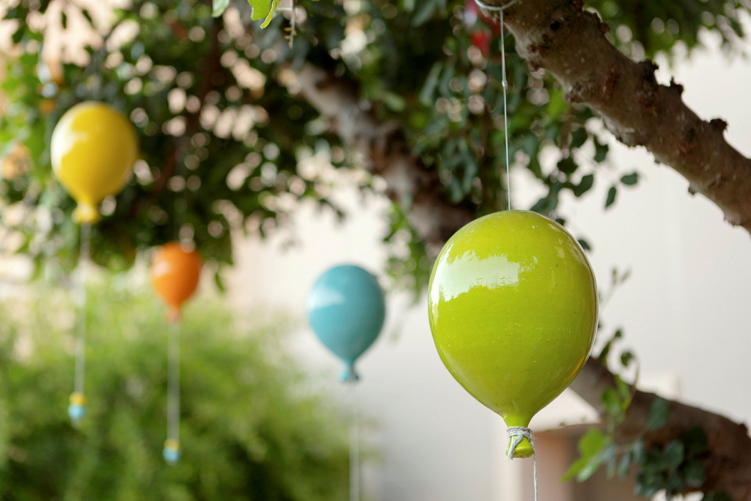 Fargerike dekorasjoner formet som luftballonger henger i et tre. (AI-generert tekst)