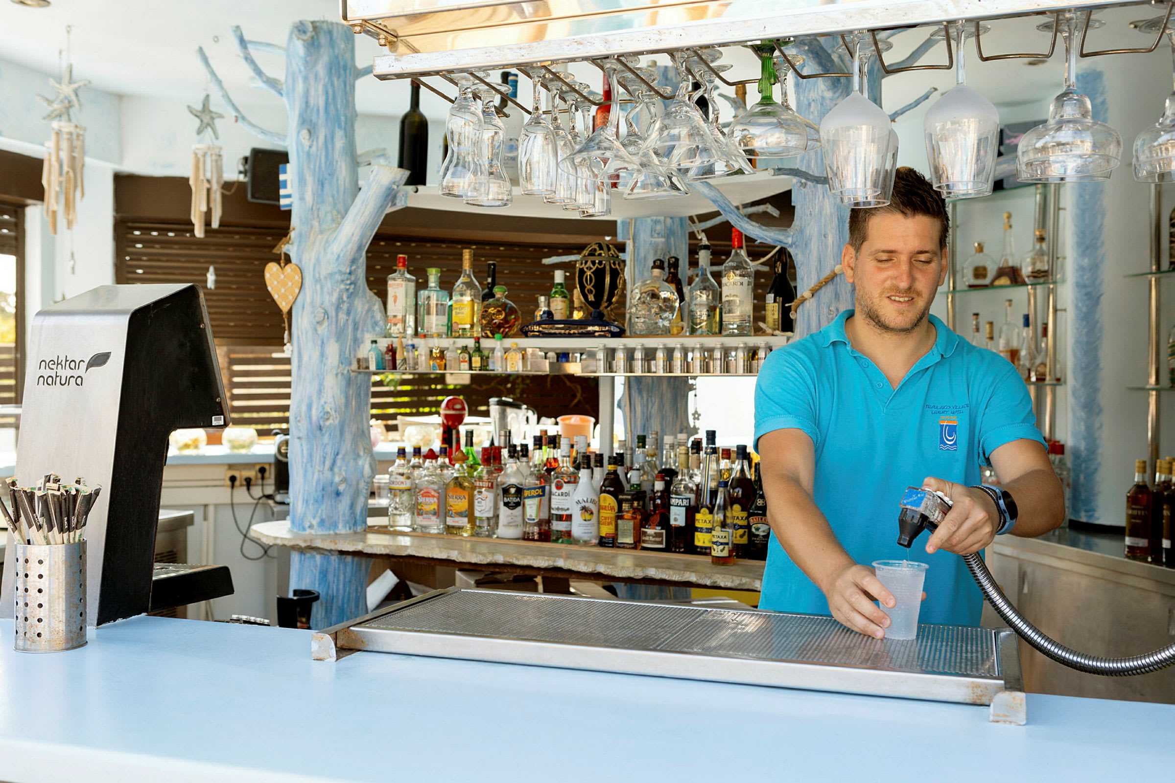 En bartender fyller et glass med en drikke ved en bar. (AI-generert tekst)