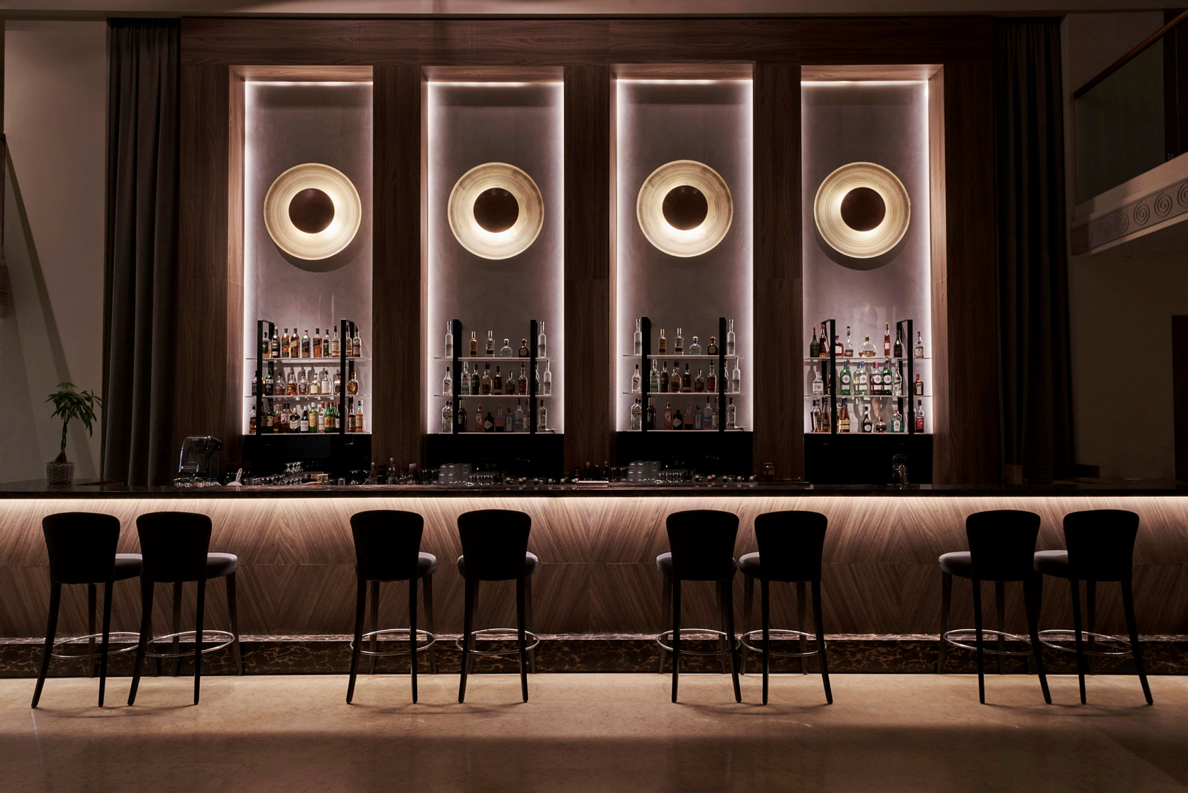 Elegant hotellbar med høye stoler og flasker oppstilt bak disken. (AI-generert tekst)