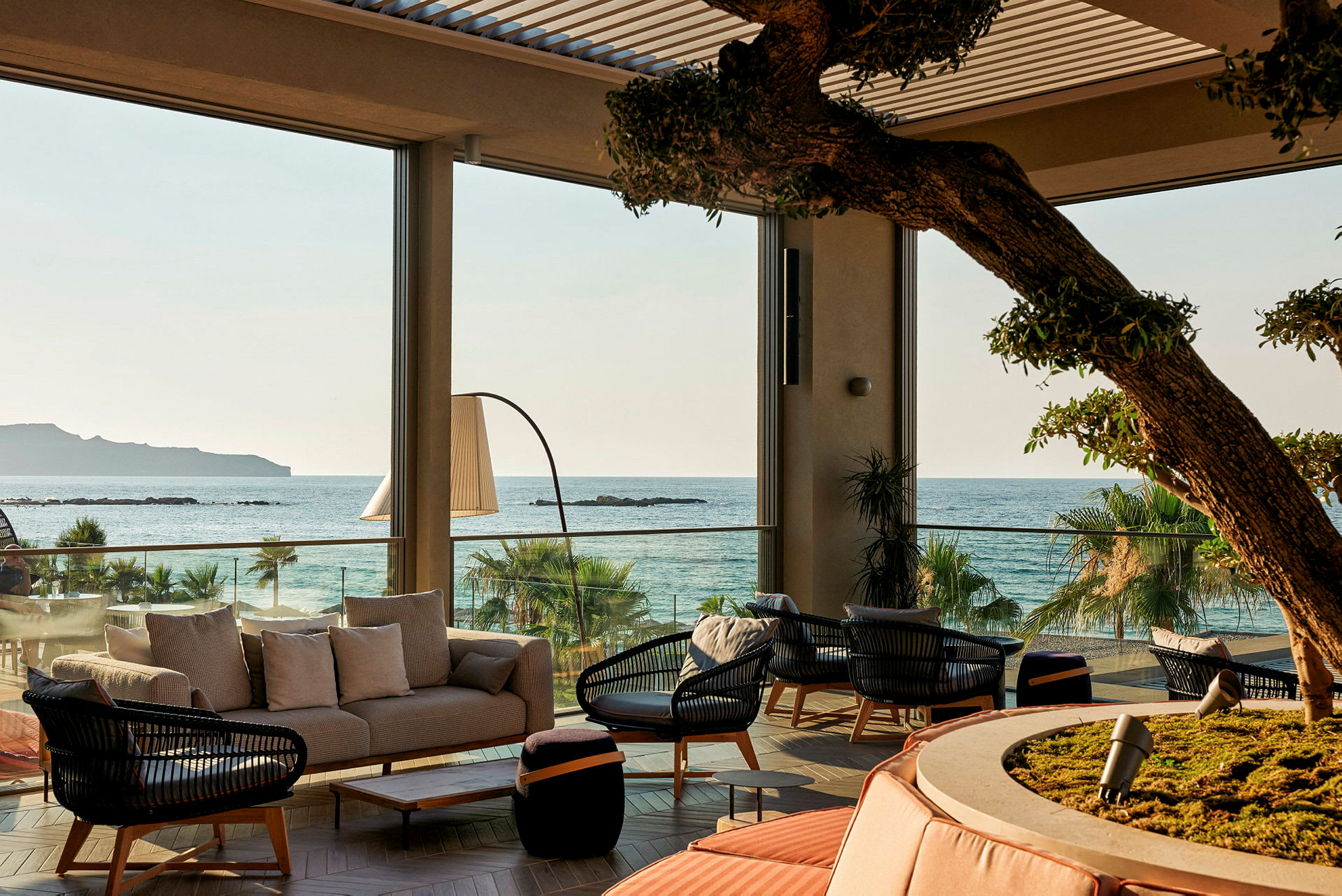 Utsikt over en møblert lounge med havet i bakgrunnen. (AI-generert tekst)